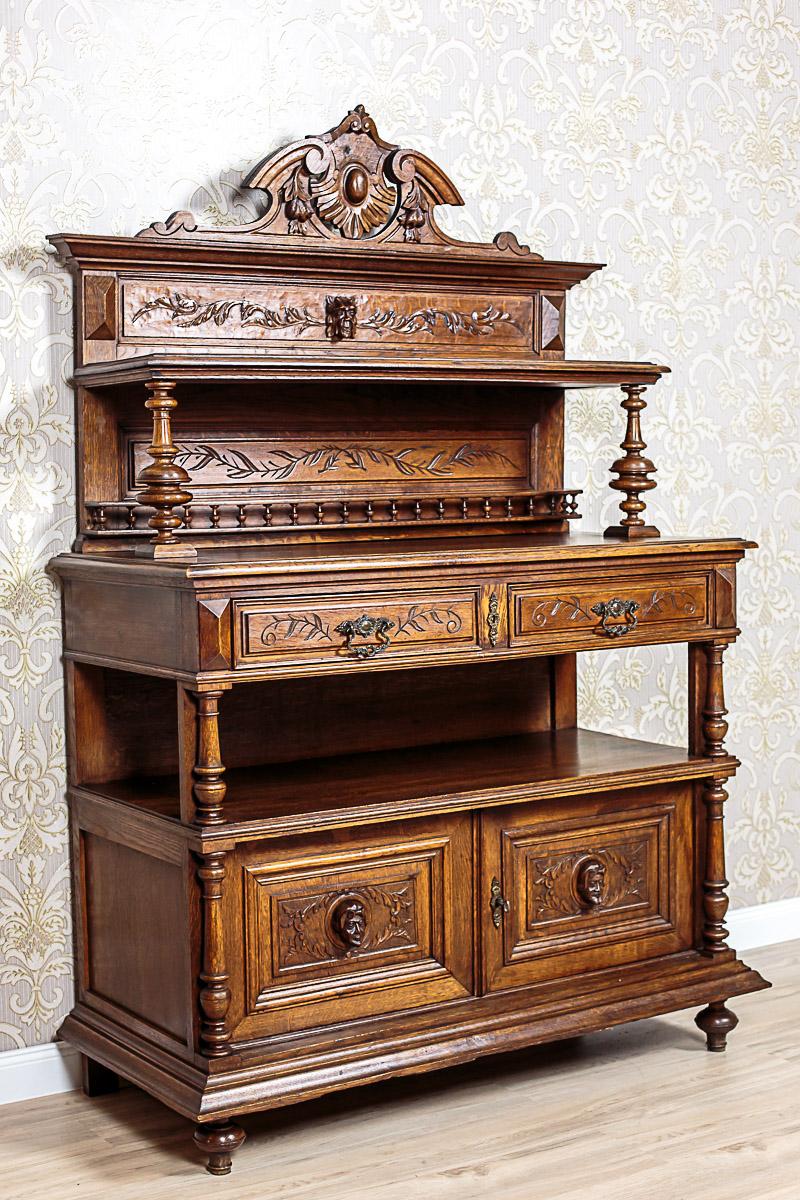 A piece of furniture from 1920, composed of a base and an upper section.
The base is divided into a two-door chest part and two drawers above it, separated with a niche, which are supported on balusters.
The upper setting is in the form of a