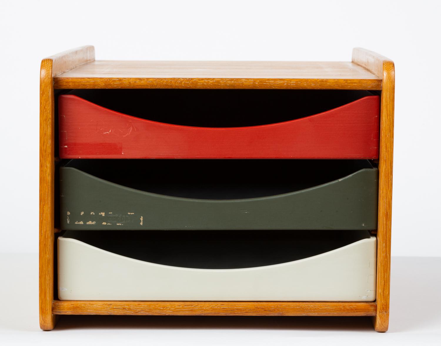 Danish-designed, Swedish-made desk organizer by Børge Mogensen for Karl Andersson & Söner from the late 1950s or early 1960s. The small box has a case of solid oak with rounded corners and raised edges. Three painted drawers in brick red, charcoal