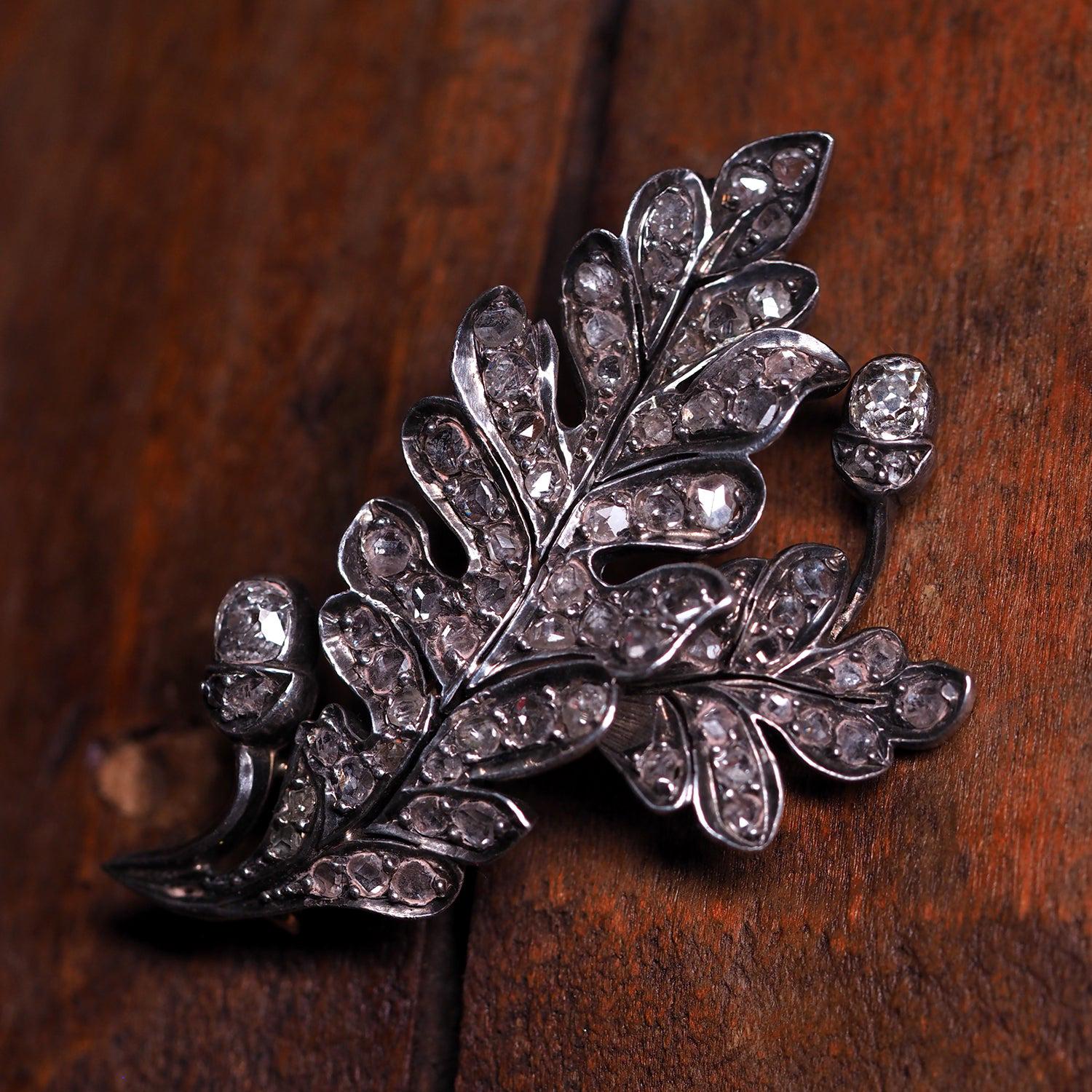 Eine diamantene Eichenblatt-Brosche aus der Mitte des Viktorianischen Zeitalters, um 1860. Fassung aus Gelbgold und Silber, Länge 45 mm

Gestaltet als Büschel von zwei Eichenblättern, in abgestufter Größe und mit alten Diamanten im Kissenschliff