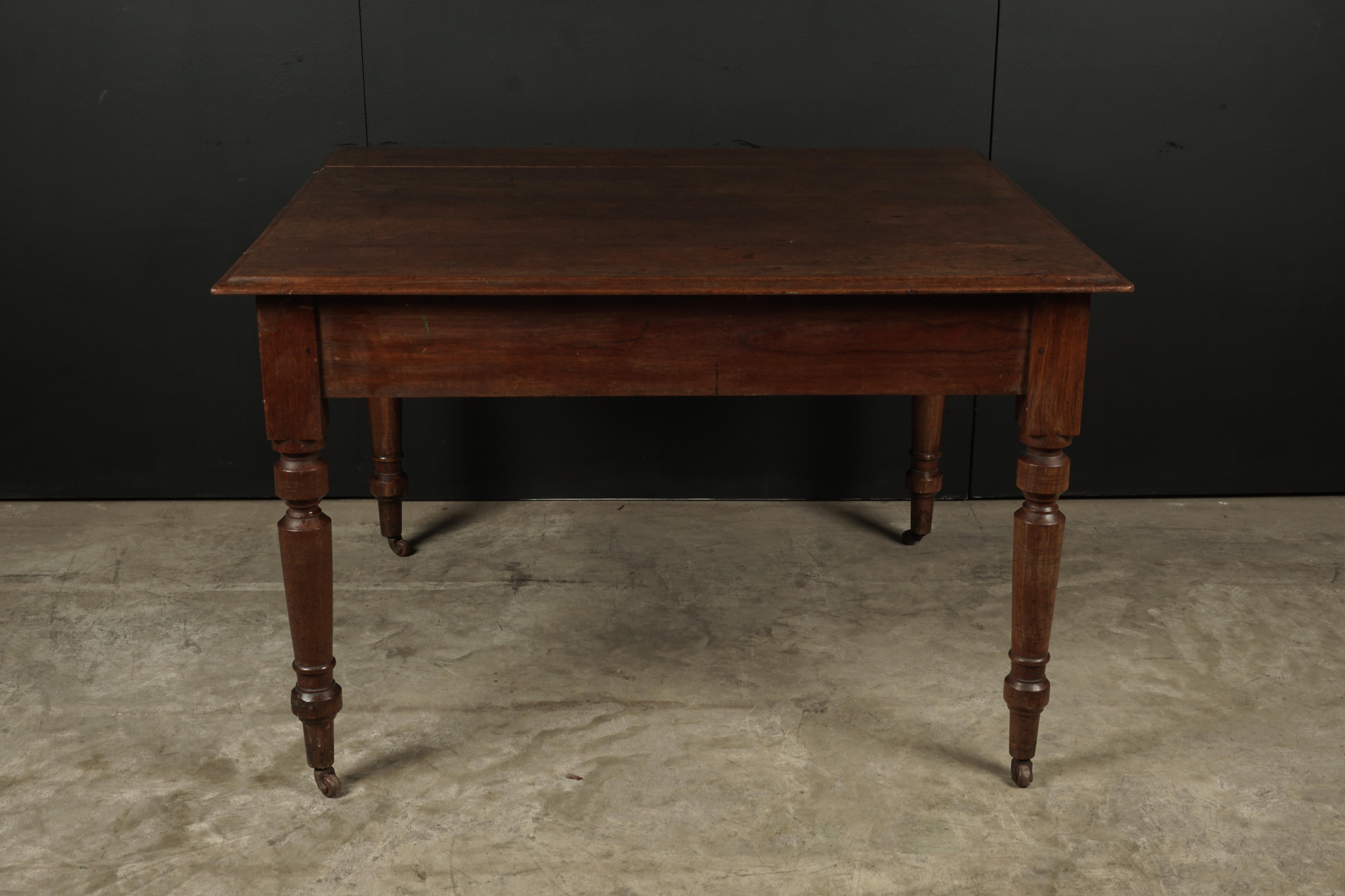Solid oak dining table from France, circa 1920. Almost square shape with original castors on feet. Light patina and wear.