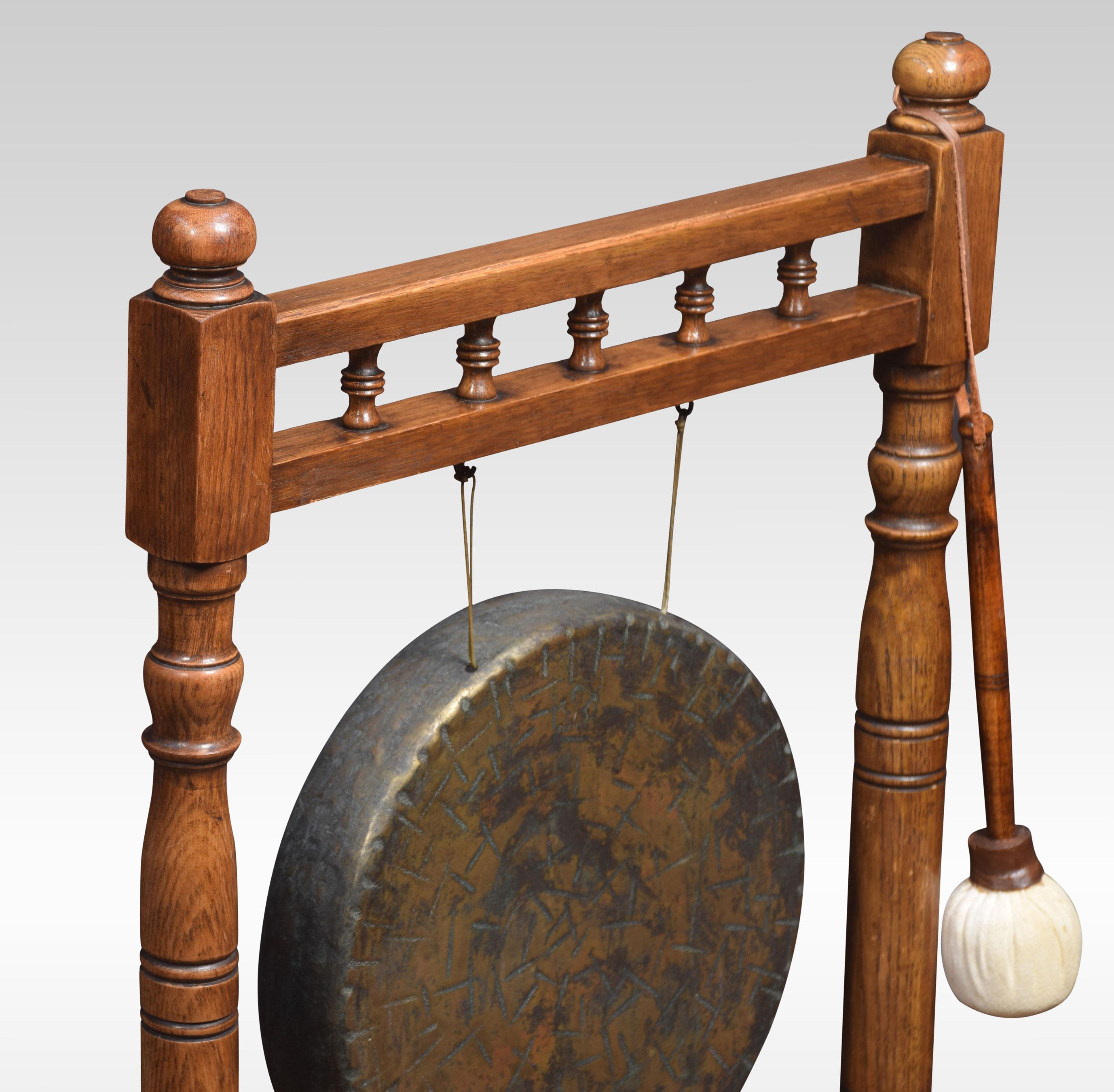 Oak framed brass dinner gong and beater, the stand having carved finials above two turned supports having suspended brass gong to centre raised up on platform base.
Dimensions:
Height 36 inches
Length 22 inches
width 13 inches.