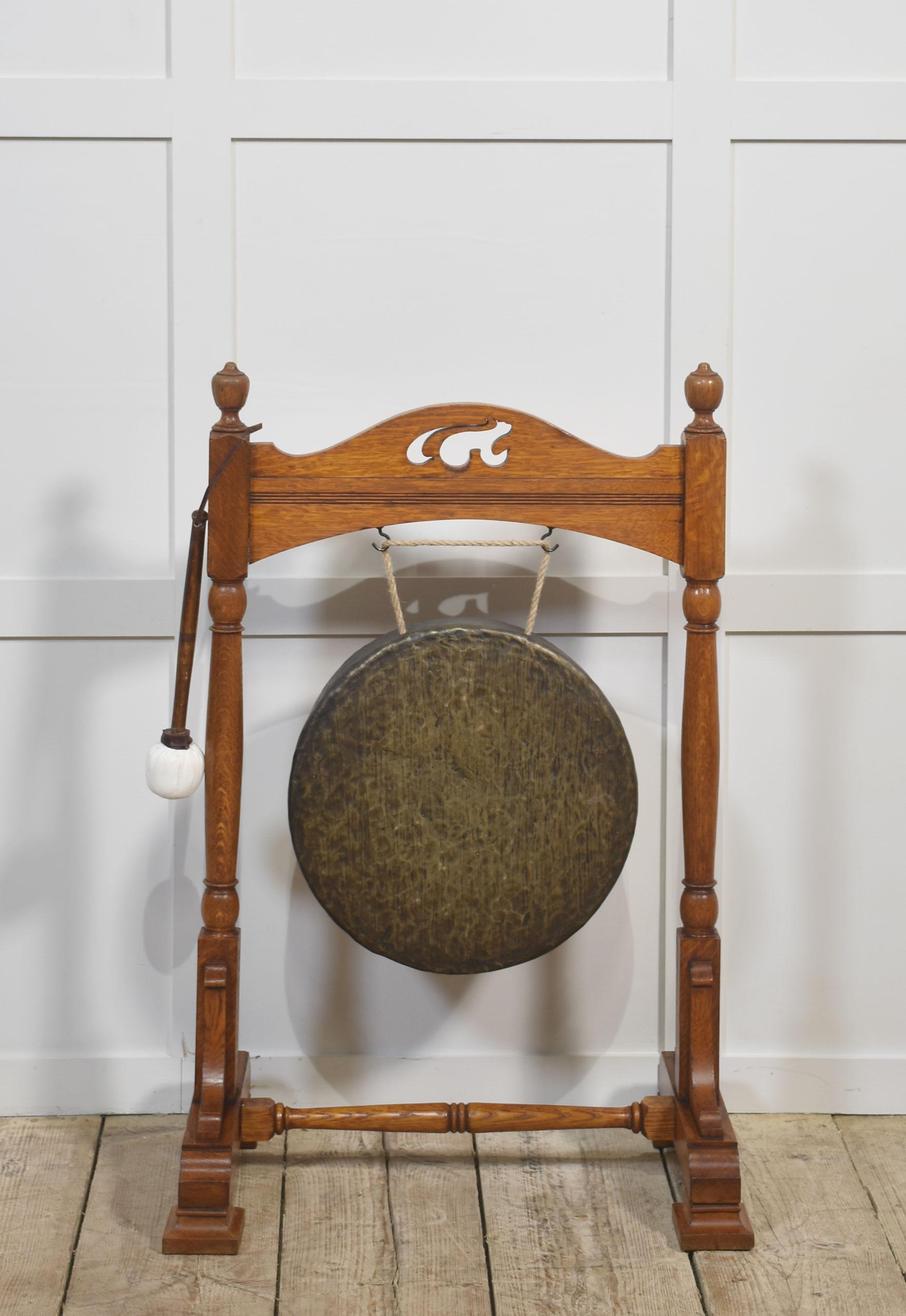 Un raffinato gong antico in quercia con una splendida struttura in quercia massiccia con supporti torniti e una barra decorativa con taglio a traforo. La struttura presenta una patina ricca e calda e poggia su robusti piedi a mensola uniti da una
