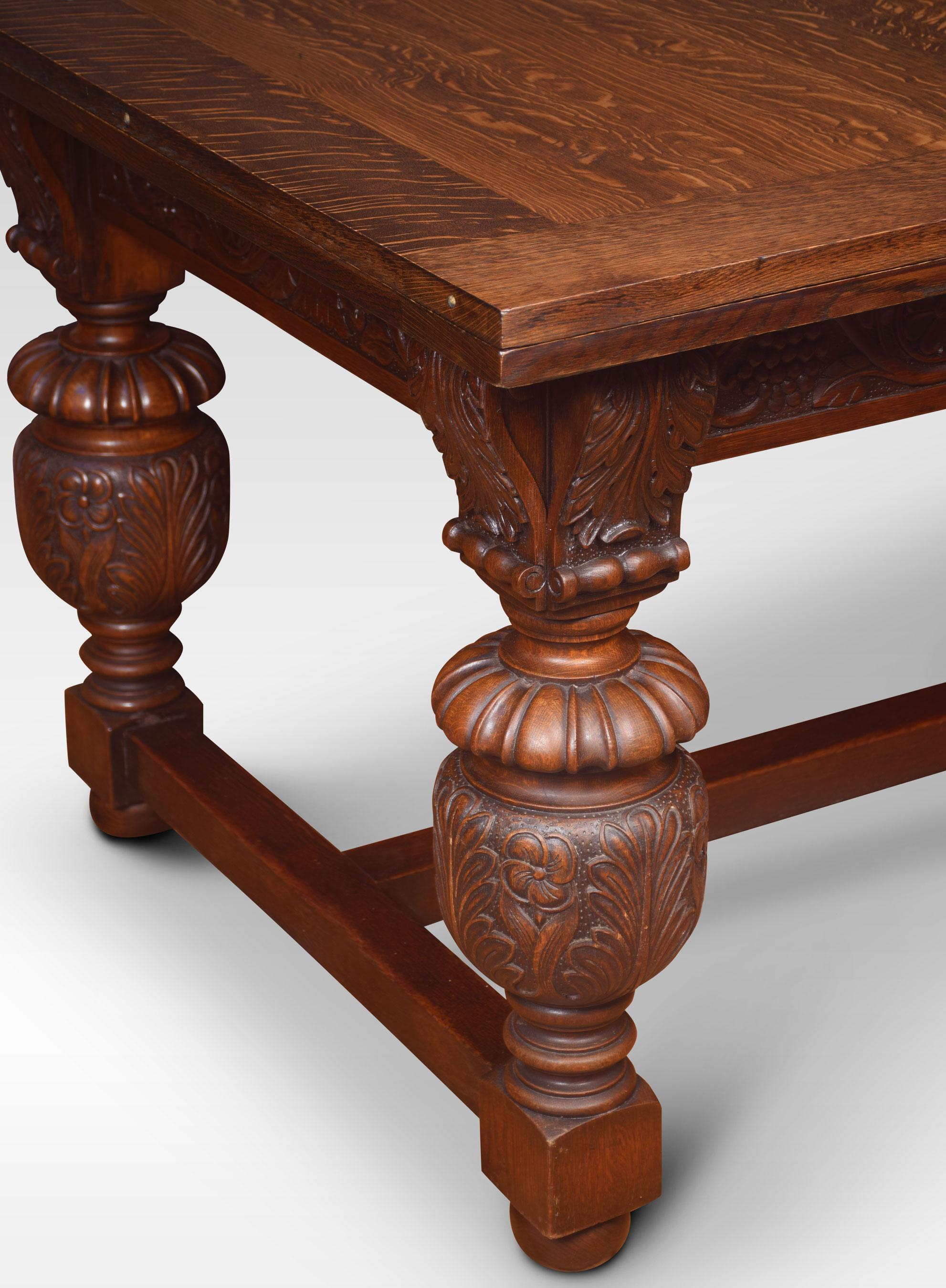 An impressive Elizabethan style oak draw-leaf table of generous proportions. The thick plank top having pull-out leaves to each end above a strap-work frieze with scrolling foliated carving raised on bulbous cup & cover legs leading down to block