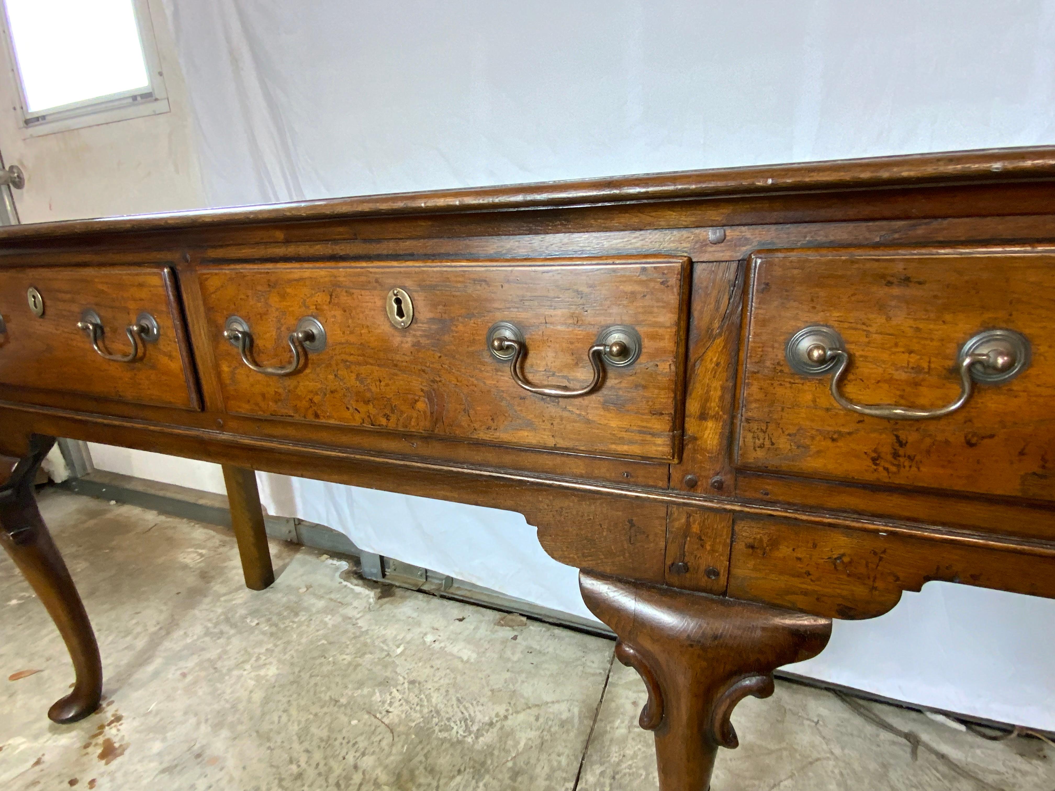 A very nice Georgian five legged four drawer Oak dresser base.  This piece is exceptionally nice because of its long length and that most of these bases were made with three drawers.  One board top with three cabriole legs ending in nice wide pad