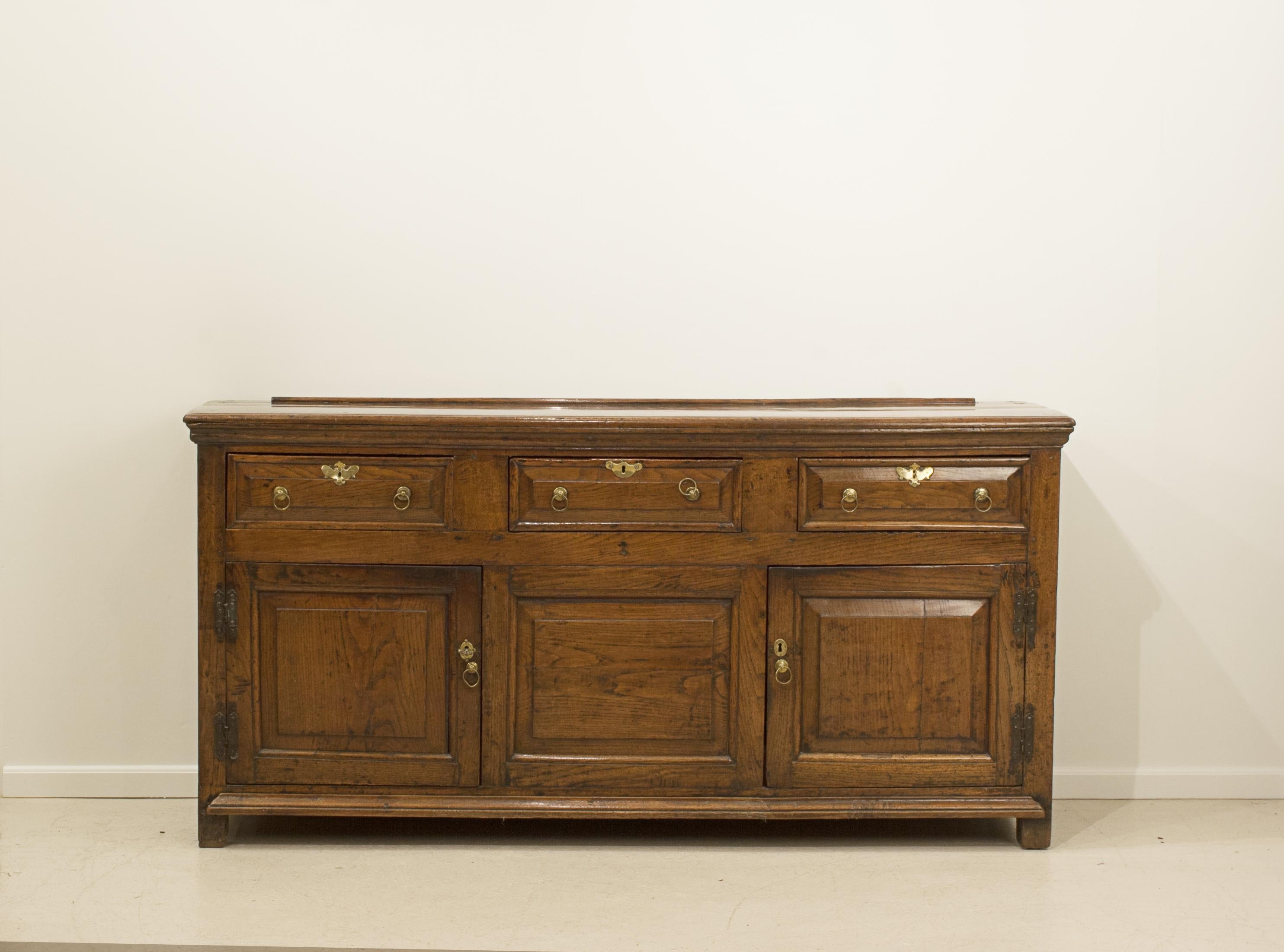 Antique oak sideboard.
A superb early 19th century antique welsh oak dresser base, sideboard. The dresser base with three drawers over two cupboards with fielded panel doors. The sideboard with brass handles and the top with plate rack. Raised on