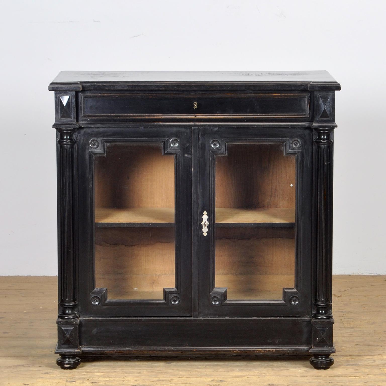 An oak French Empire style dresser from circa 1920, with a drawer and display part. The cabinet has the original antique glass. Pilaster detailing on the edge of the sideboard and turned ball feet.