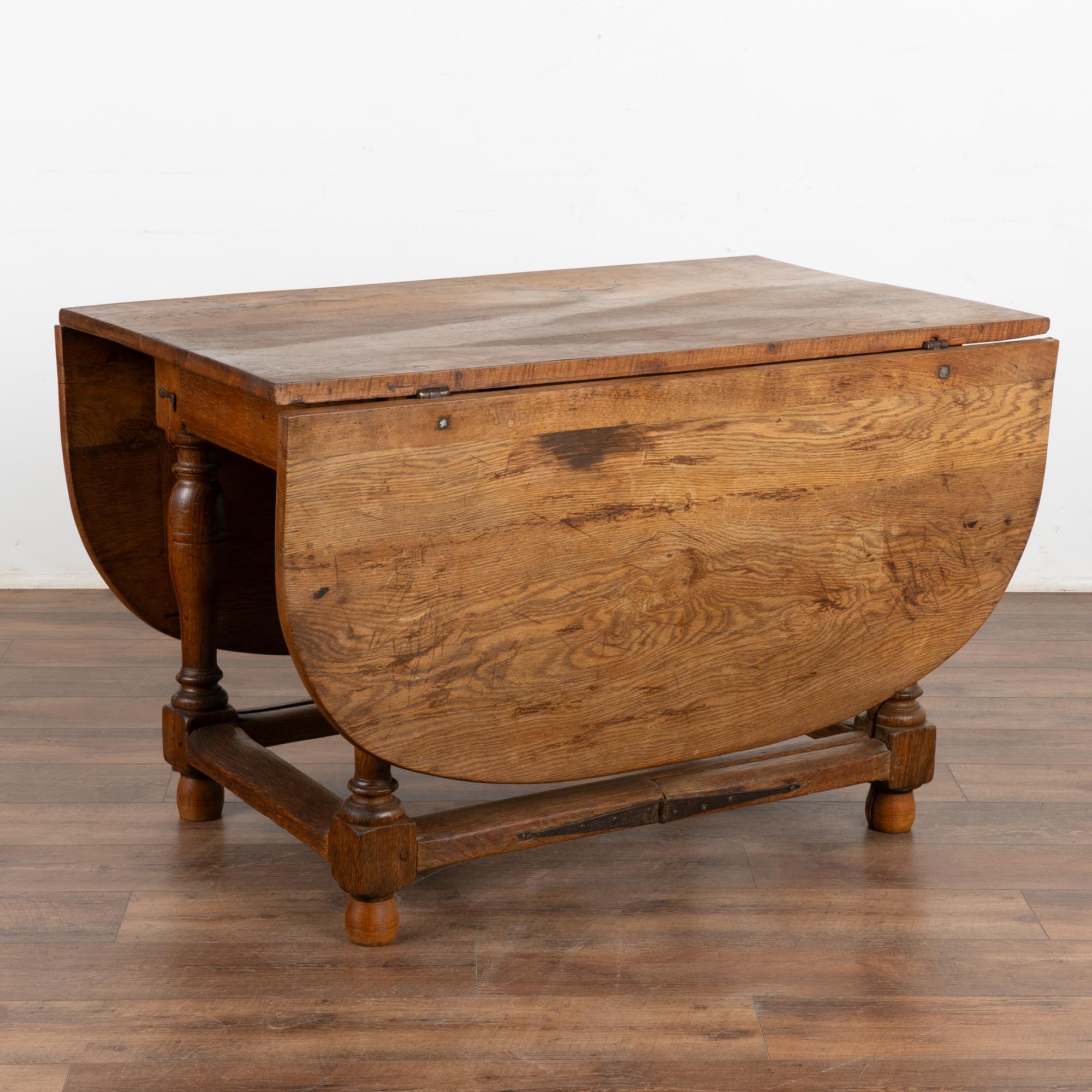 Cette belle table de cuisine ou de salle à manger à pied d'appui est munie de deux abattants qui permettent de l'utiliser également comme console.
Le grand plateau ovale est doté de deux feuilles, de sorte que lorsqu'il est fermé, il sert de table