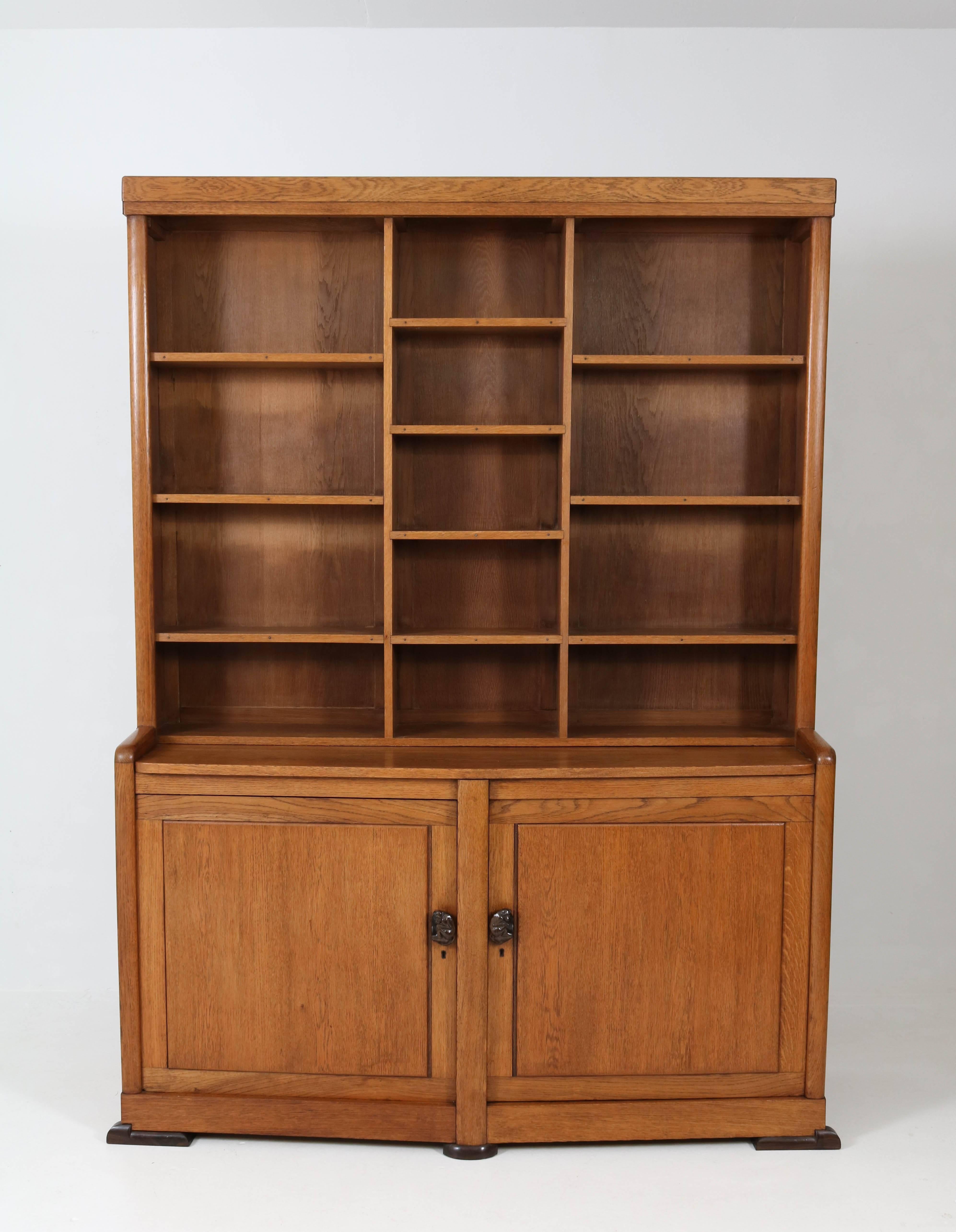 Offered by Amsterdam Modernism:
Stunning and very rare Art Deco Amsterdam school bookcase, 1920s.
Solid oak and standing on solid ebony Macassar legs.
Please note the very rare door handles, two original solid ebony Macassar carved monkeys.
In good