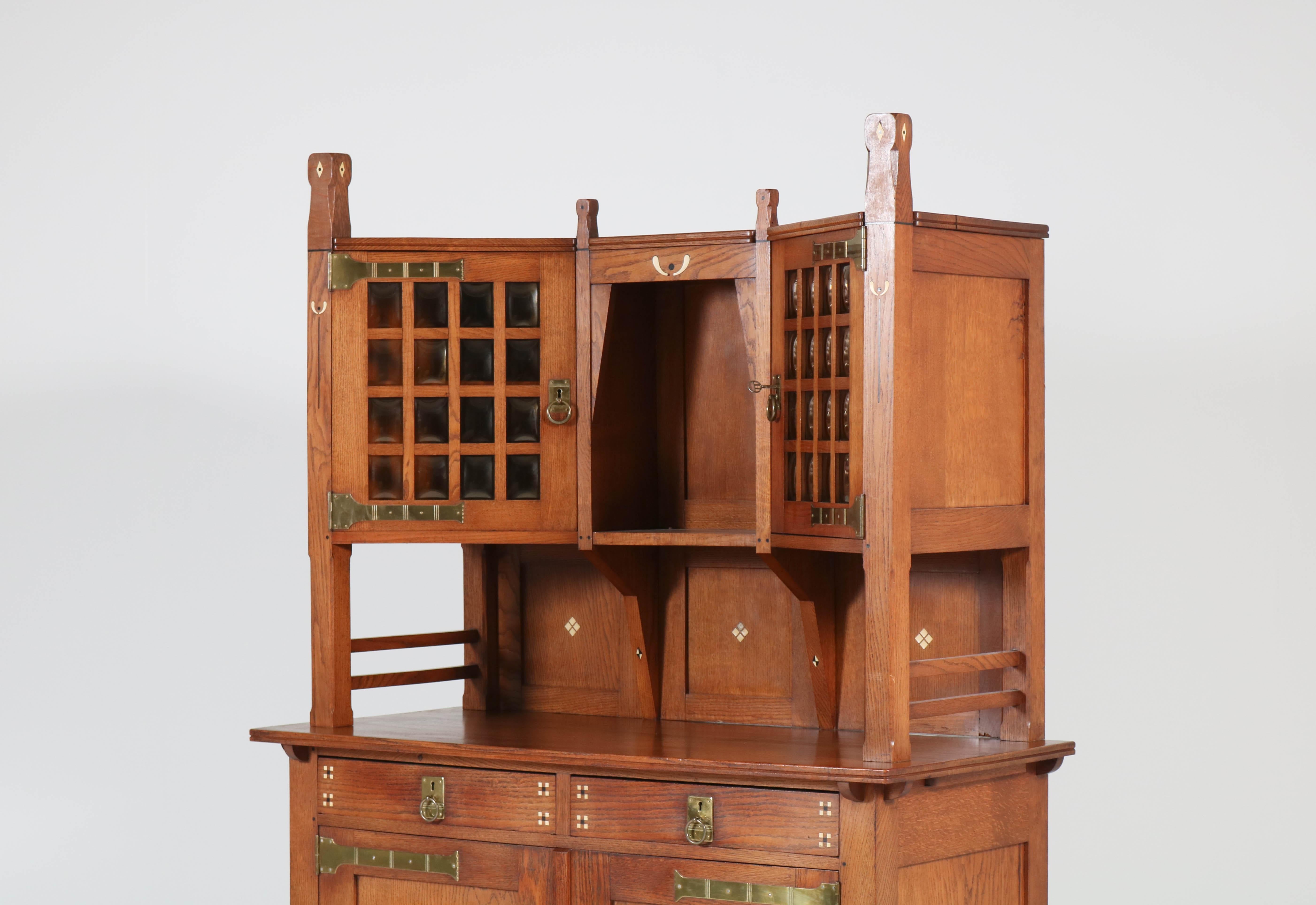 Stunning Art Nouveau Arts & Crafts sideboard.
Attributed to Onder den Sint-Maarten
Striking Dutch design from the 1900s.
Solid oak with original brass hinges and inlay.
Original and wonderful shaped glass in the two doors on the top piece.
In