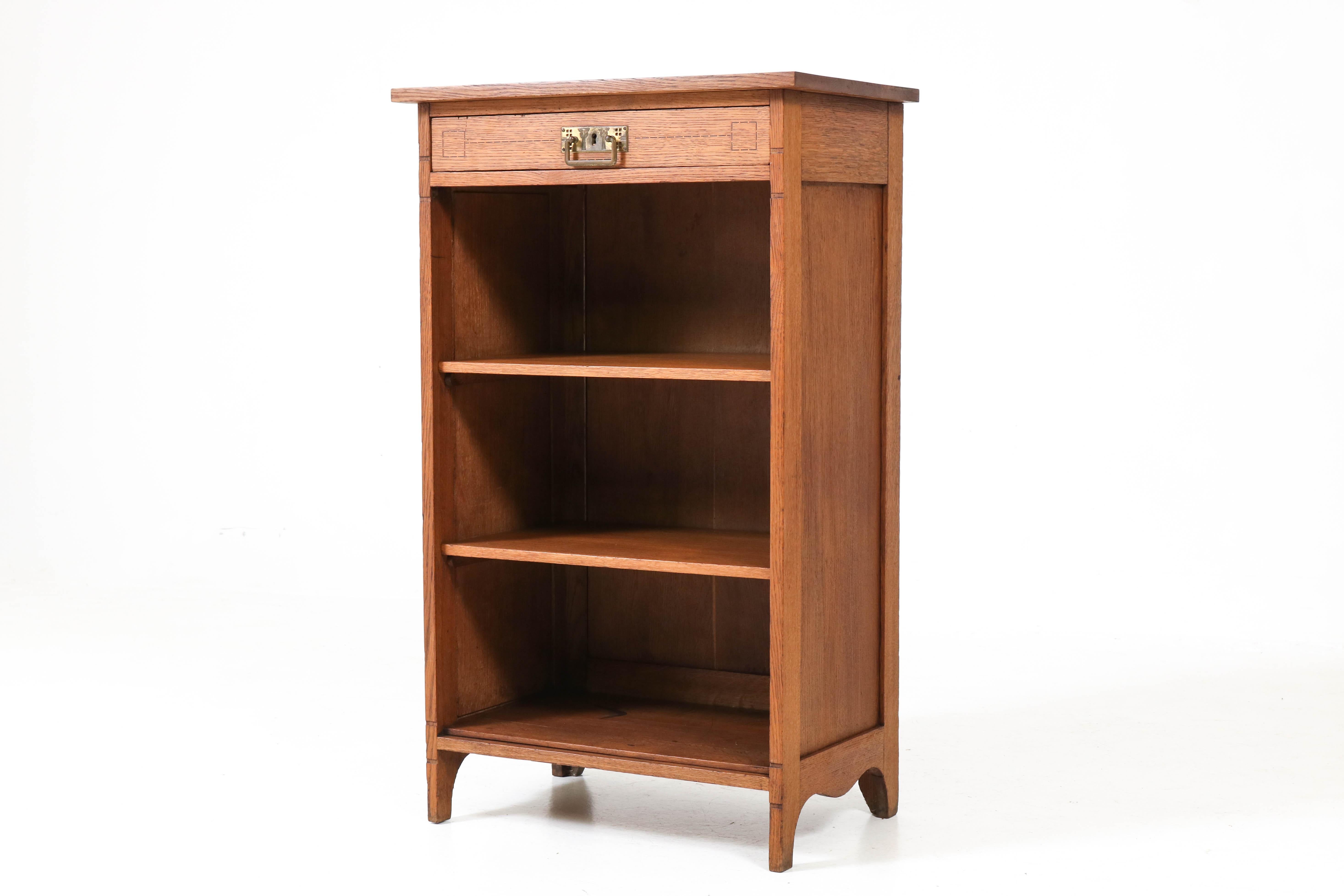 Elegant Dutch Art Nouveau Jugendstil open bookcase.
Solid oak with original solid brass handle on the drawer with inlay.
Two original solid shelves and solid oak bottom with some stains.
Not to be noticed when the bookcase is filled with