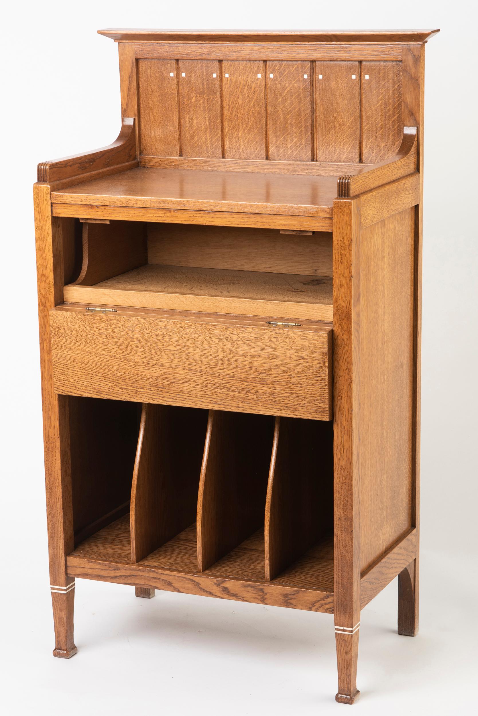 A Dutch secessionist music cabinet.
Oak with inlaid small, square insets of bone.
Panelled top above a short secretaire drawer, set with black hammered metal Art Nouveau shaped hinges.
With 4 vertical compartments to the lower part.
The feet