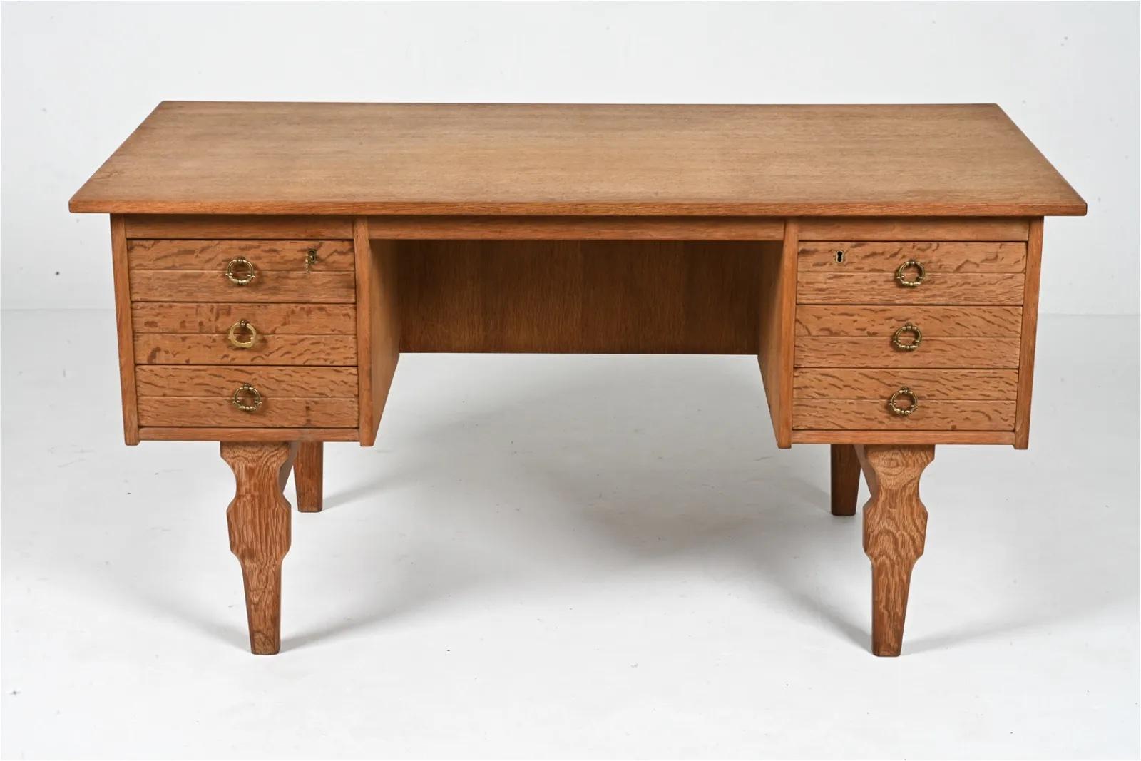 Exceptional executive desk in quarter-sawn white oak, featuring gothic-inspired panel moldings, a scalloped apron and thick sculpted legs.
Six dovetailed drawers on one side and a lockable cabinet flanked by two alcoves on the reverse