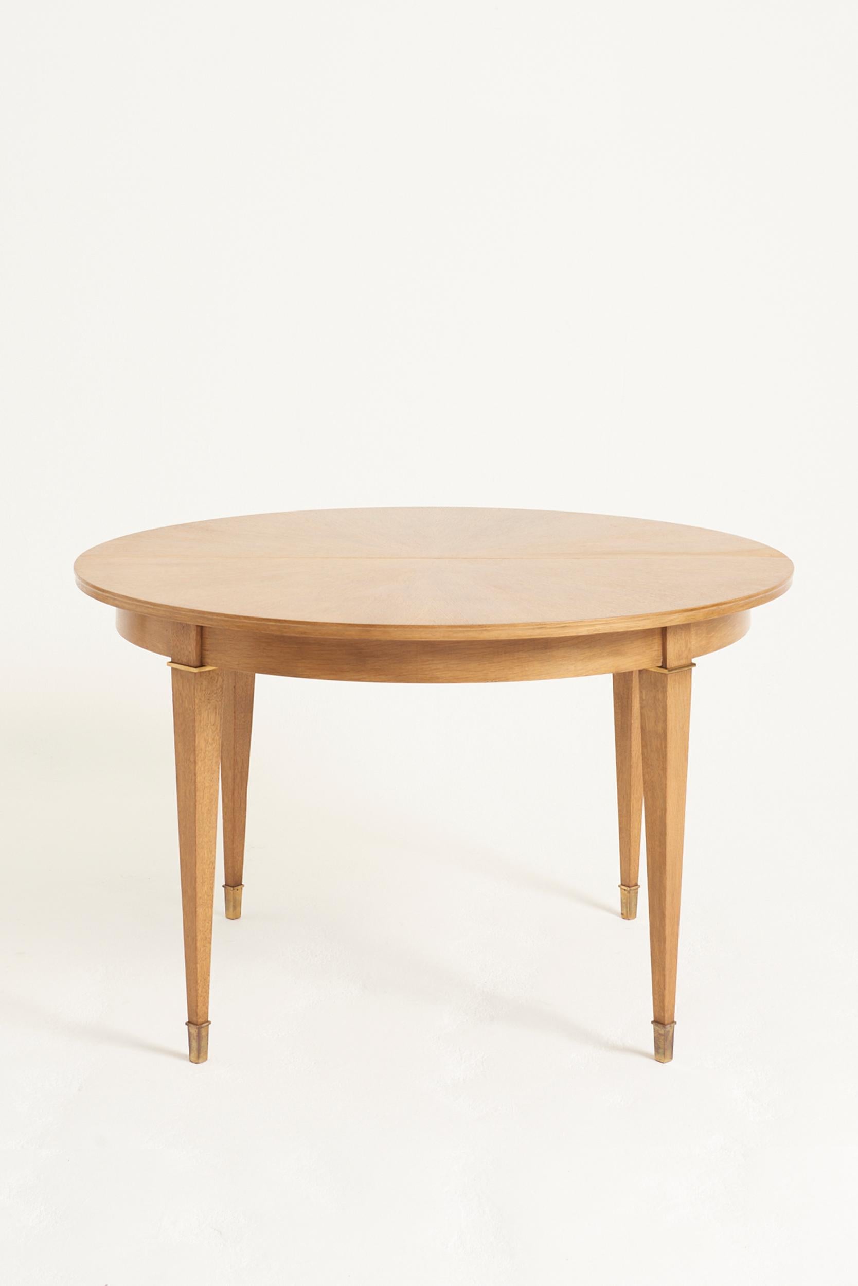 An Art Deco oak and brass mounted circular and extending dining table, possibly by Jacques Adnet. Comes with 2 extension leaves.
France, Circa 1940
73 cm high by 115 cm diameter. 
With 1 leaf: 160 cm wide by 115 cm depth. 
With 2 leaves: 205 cm wide