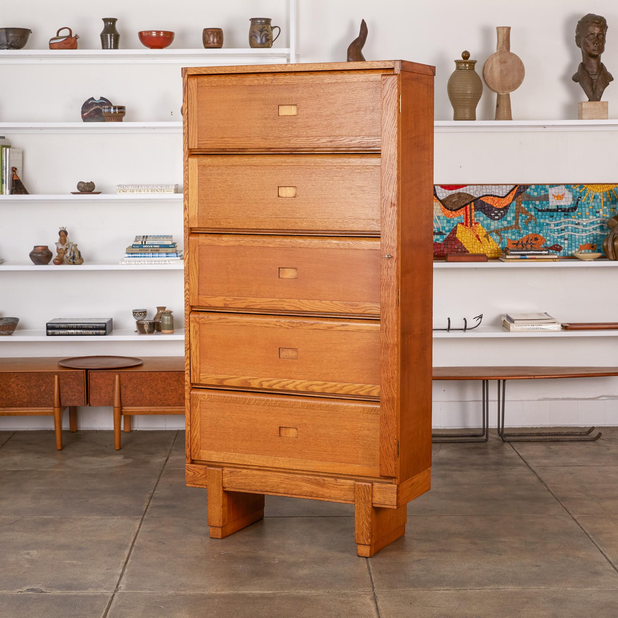 Oak filing cabinet by ER Staverton, UK, circa 1950s. The cabinet features a solid oak frame that sits atop chunky oak block legs. It has five vertically stacked hinged doors that flip up to reveal individual compartments separated by two narrow