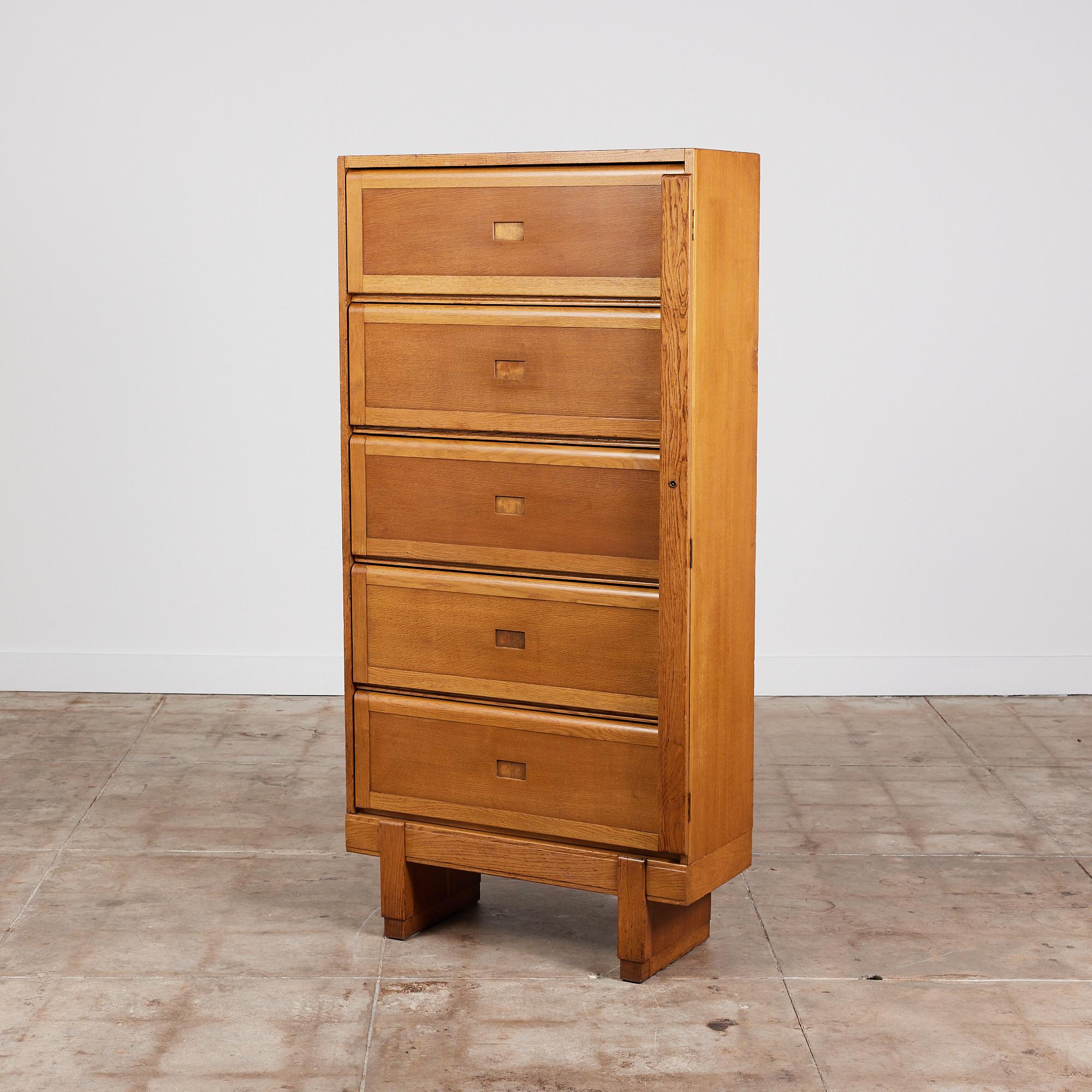 Oak filing cabinet by ER Staverton, UK, c.1950s. The cabinet features a solid oak frame that sits atop chunky oak block legs. It has five vertically stacked hinged doors that flip up to reveal individual compartments separated by two narrow plywood