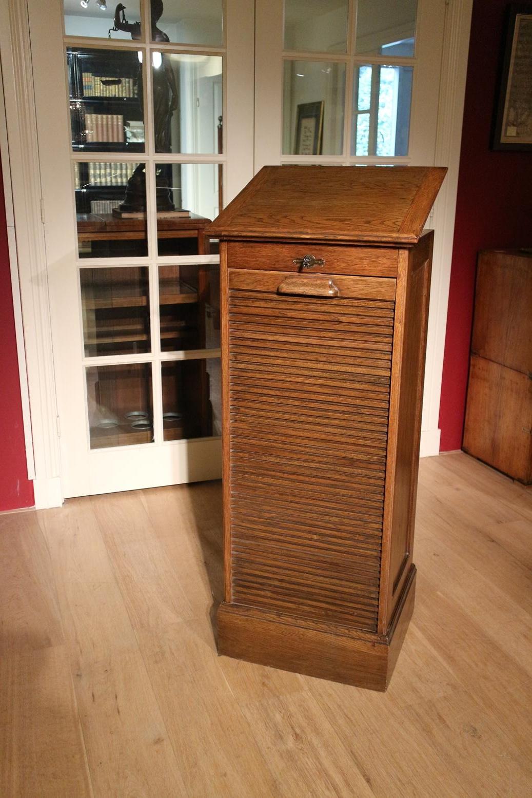 Oak filing cabinet with roller shutter. Where top can be adjusted to place a book.
Entirely in good condition.
Origin: England
Period: circa 1920
Size: Br. 49cm x D 43cm x H 115cm.