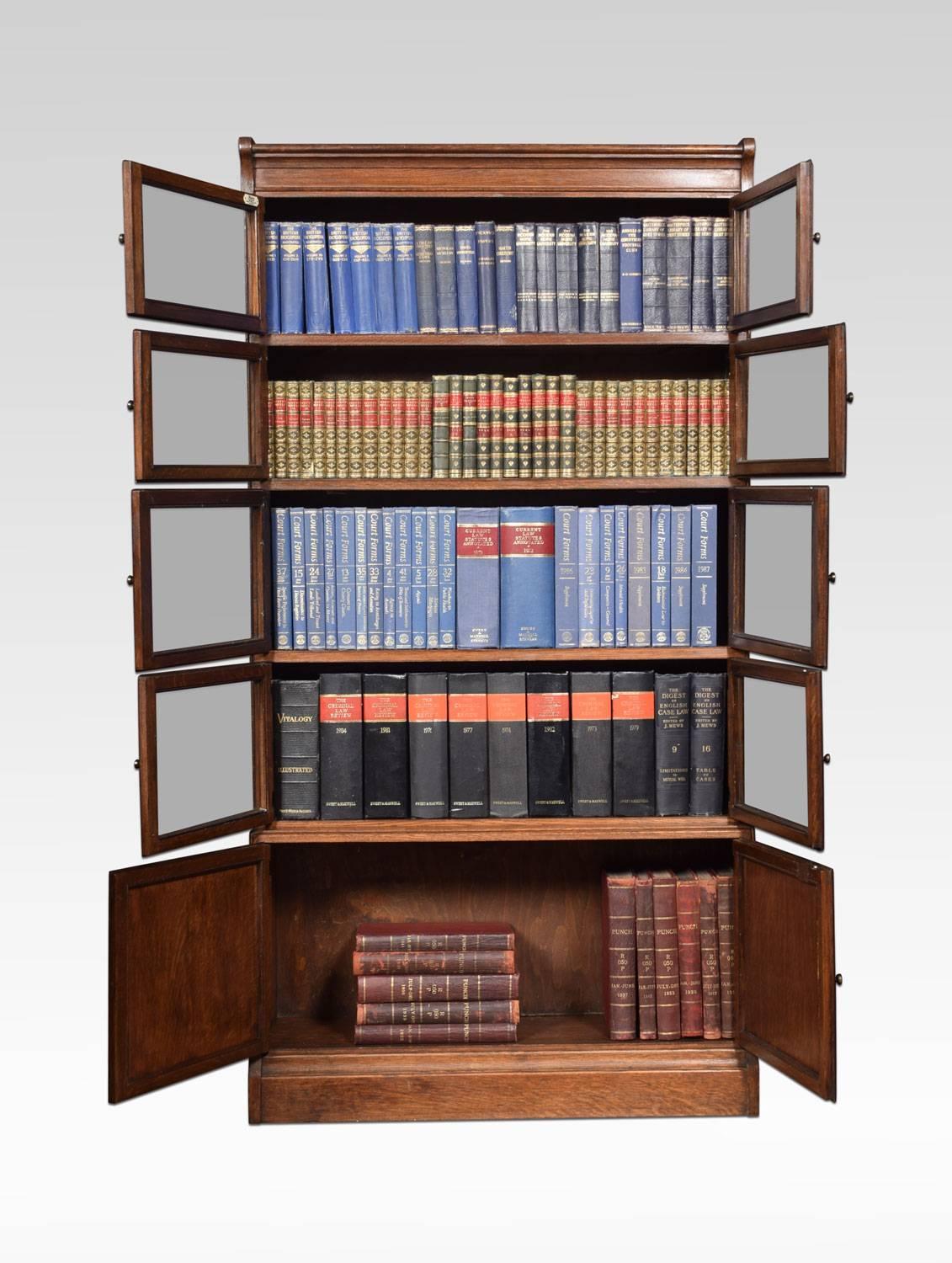 Oak five sectional bookcases by Minty Library specialist’s oxford, with a moulded top above four sections fitted with two glazed doors and brass knobs, the base section fitted with a pair of solid oak panel doors. All raised up on plinth