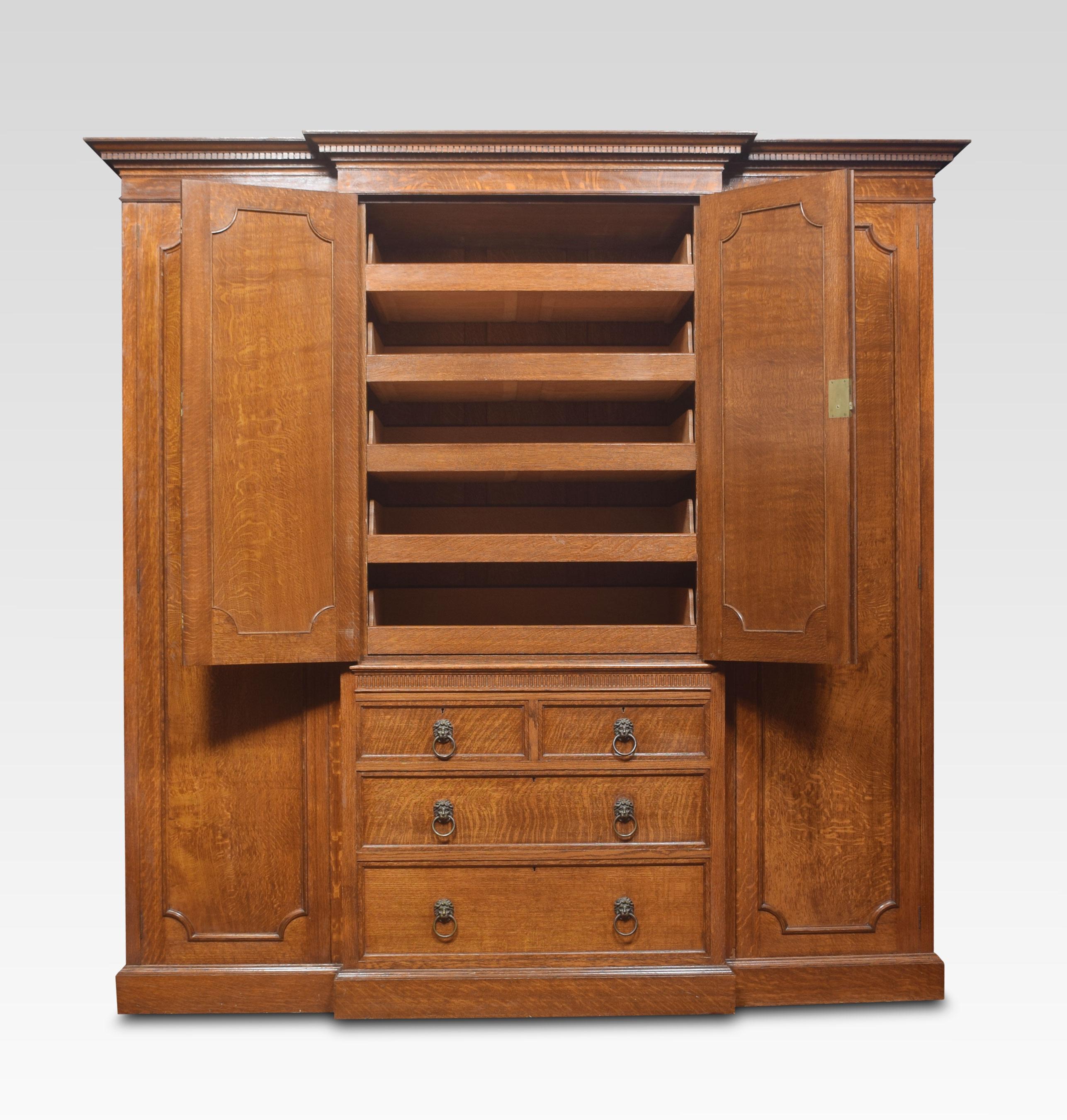 Oak four door breakfront compact wardrobe with a molded cornice, To the long outer paneled doors opening to reveal large hanging area and internal mirrors. Flanking further double doors enclosing five linen slides, above two short and two long