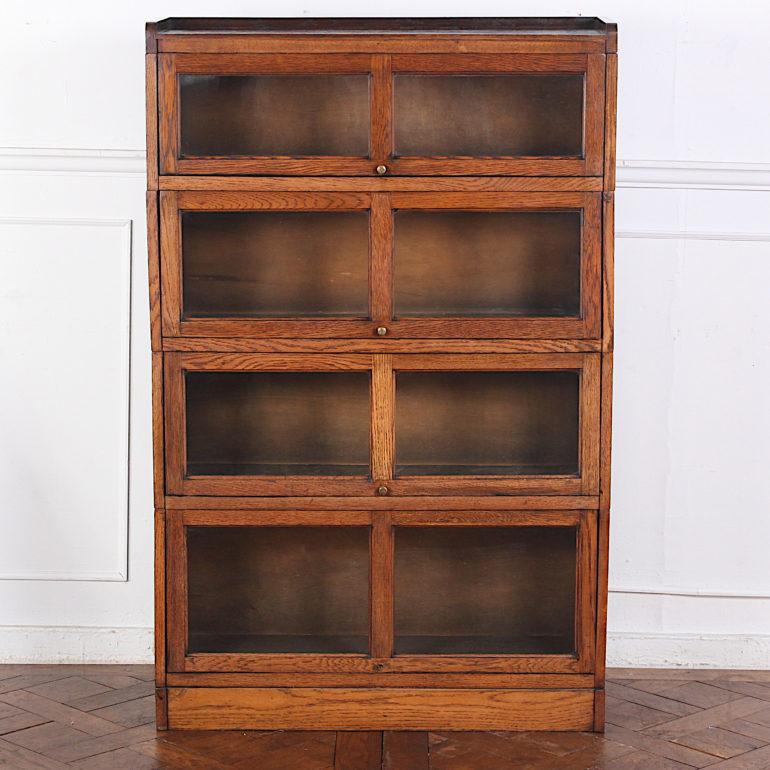 A four-section stacking lawyer’s bookcase in oak, each graduated section with a raising and retracting glass oak-framed door. 

 