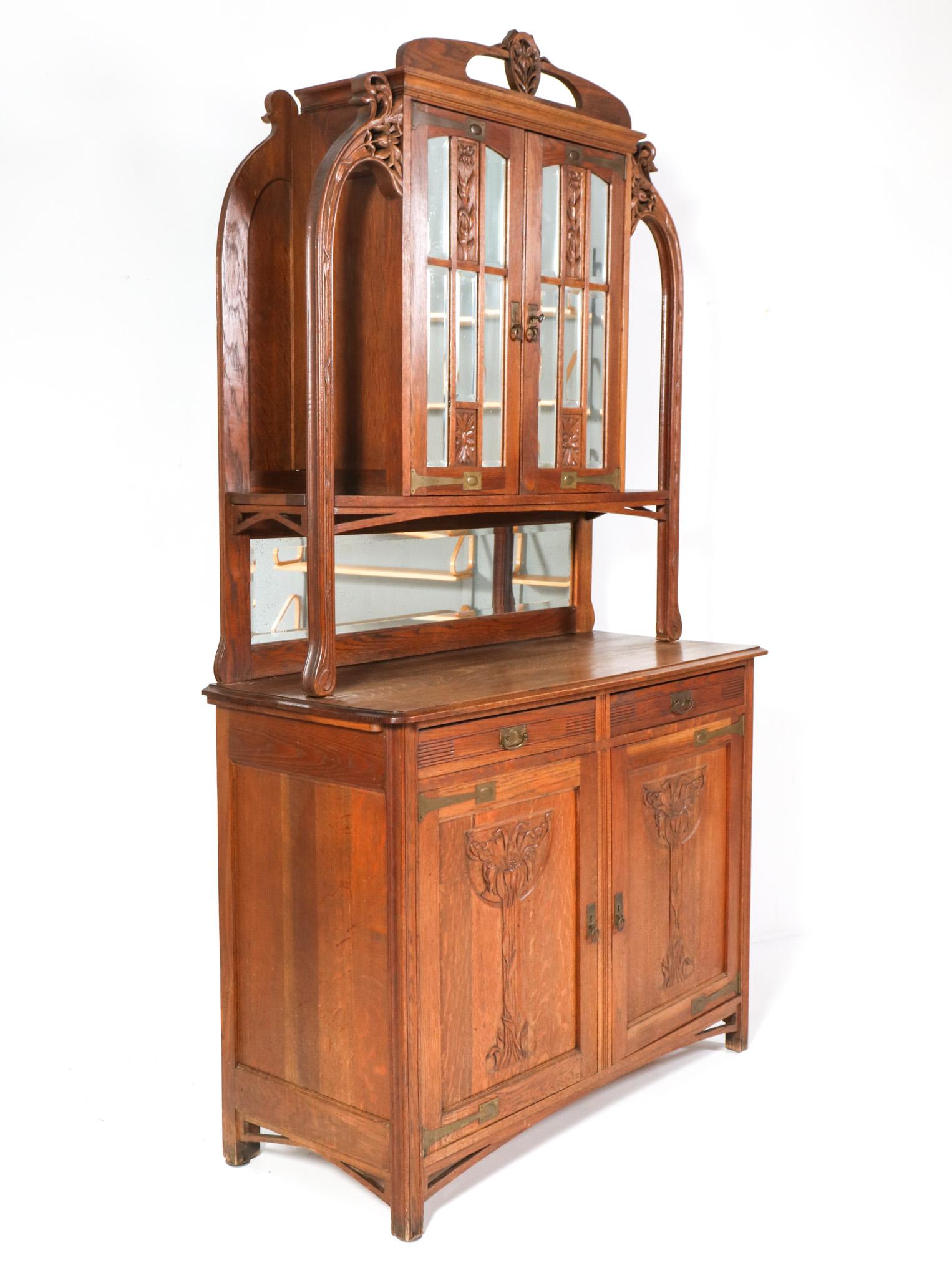 Stunning and rare Art Nouveau buffet.
Striking French design from the 1900s.
Solid oak base with two doors and two drawers and original brass handles and hinges.
Solid oak top with original beveled glass in the two doors and original brass handles