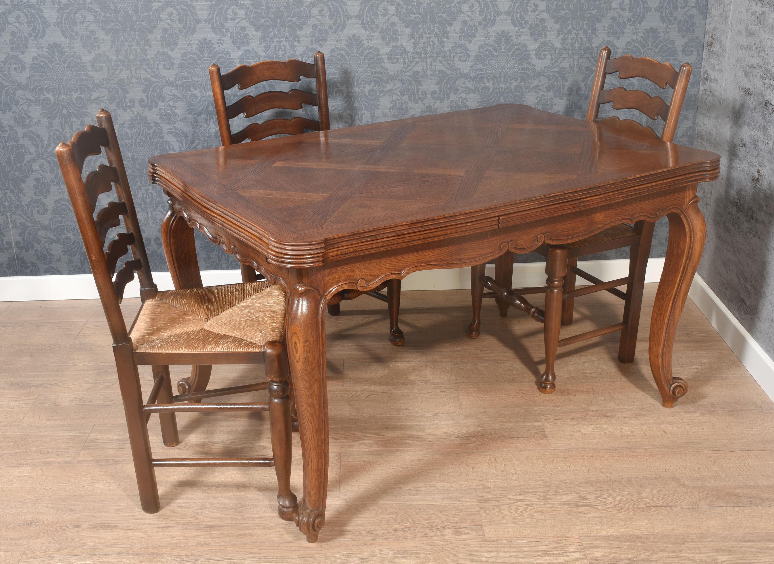 Table de salle à manger à rallonge de style provincial français, le plateau en parquet de chêne bien structuré avec deux rallonges, au-dessus du tablier sculpté en forme. L'ensemble repose sur des pieds cabriole se terminant par des pointes en