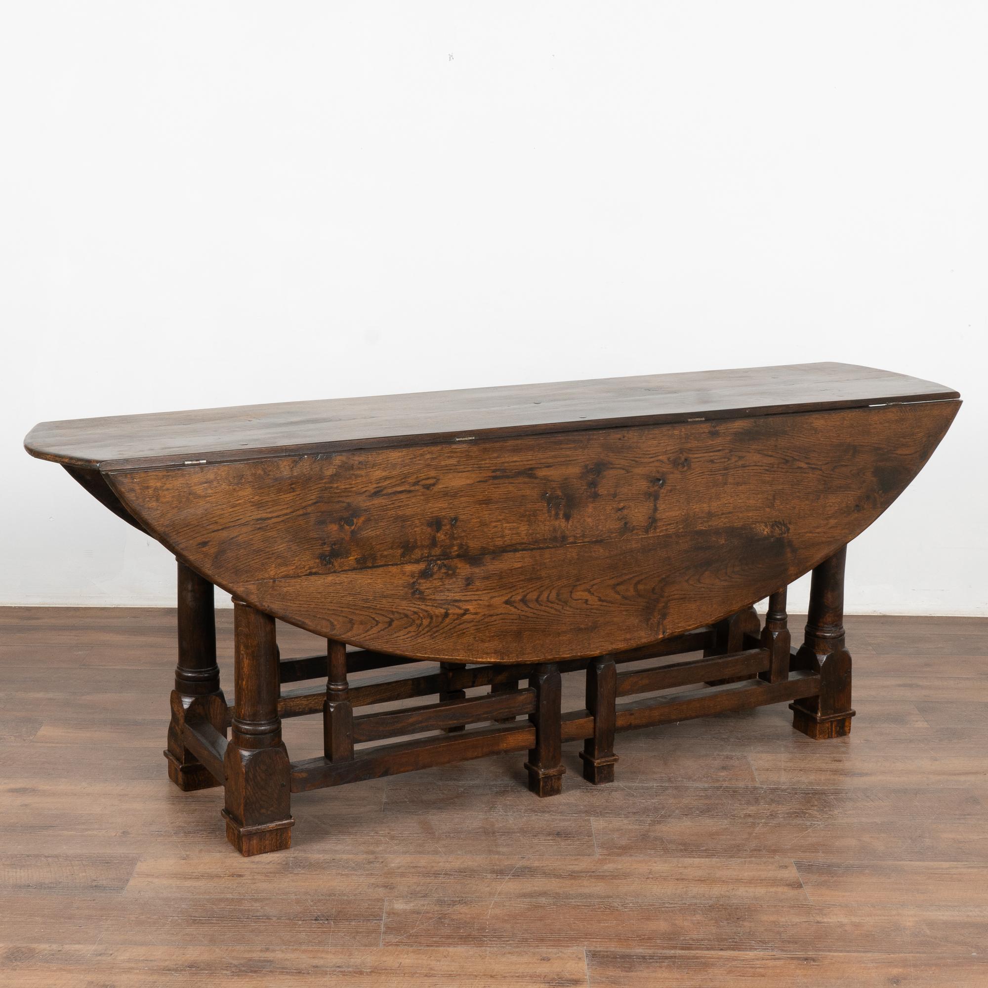 This handsome gateleg dining table is also known as an English wake table with drop leaves.
Notice the dark patina of the oak, aged and naturally distressed over generations of use and lovely turned legs.
The large oval shaped top has 2 drop leaves,
