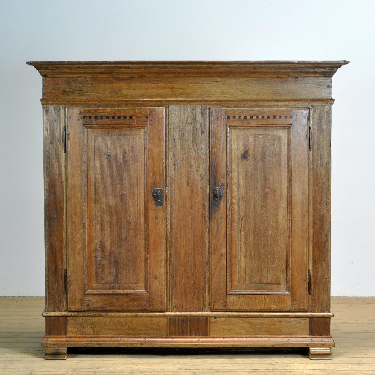 Large German cabinet from circa 1820. The cabinet is in good original condition with a beautiful patina. Solid oak two-door model with cutlery drawer and three shelves. Original fittings and keys, beautifully decorated doors with inlaid wood and