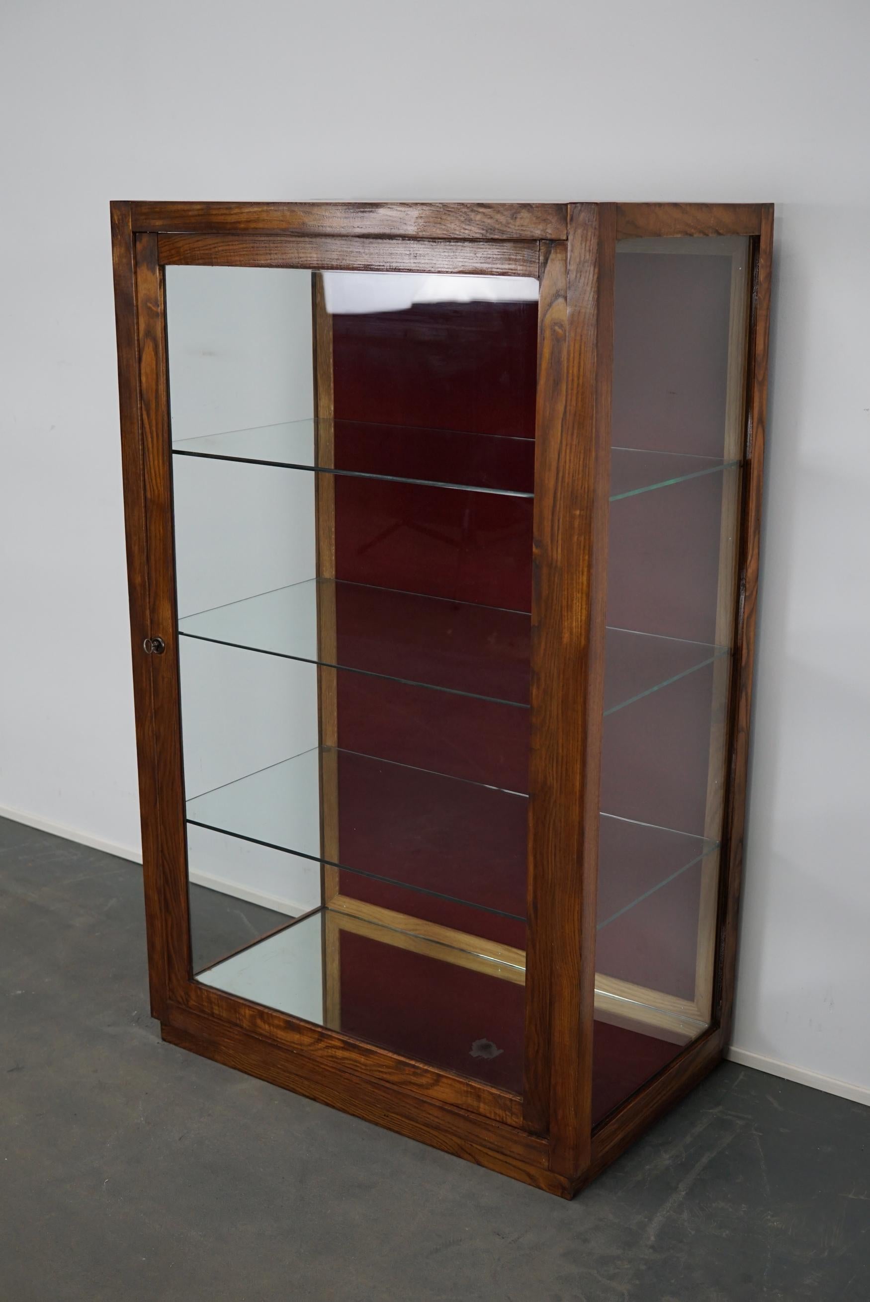 This oak shop vitrine was made in France, circa 1950s. It was made from oak with three glass shelves and a mirror in the bottom. It was used to display items in a shop.