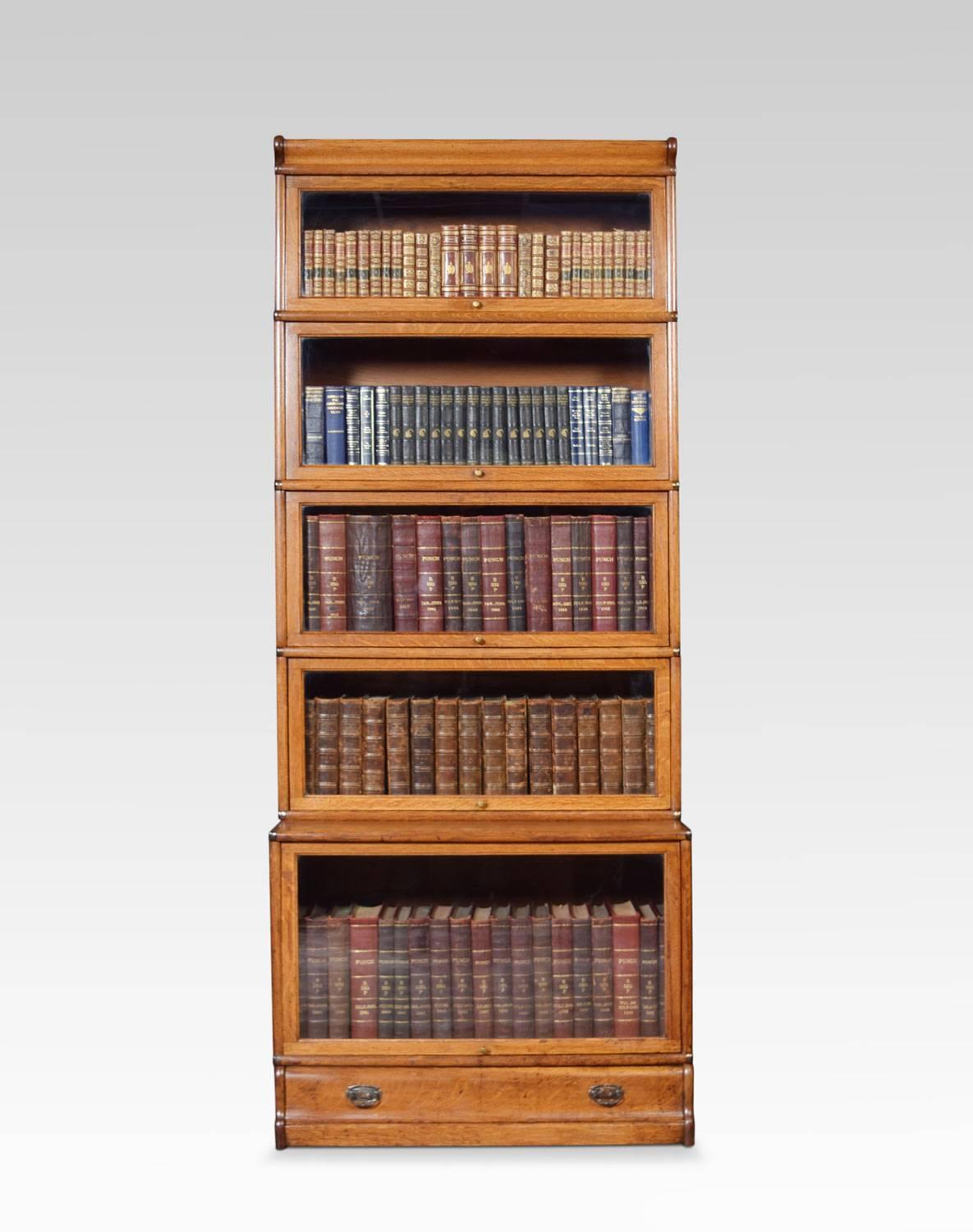 Oak five section bookcase, the moulded top above five graduated section fitted with glazed doors. All raised up on a plinth base with single long draw.
Dimensions
Height 85.5 inches
Width 34 inches
Depth 19 inches.