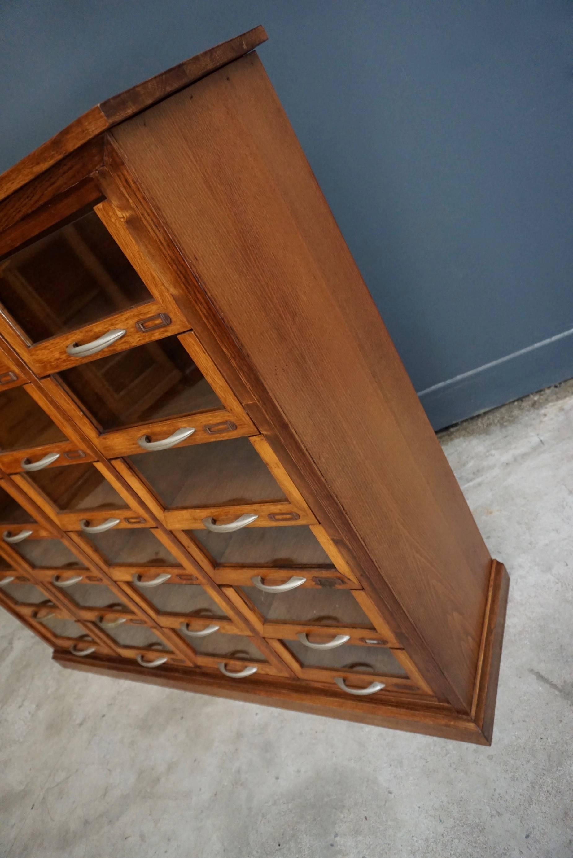 This vintage haberdashery shop cabinet originates from the United Kingdom. It is made from oak and features 24 drawers. The inside of the drawers measure: 29 x 24.5 x 11.8 cm.