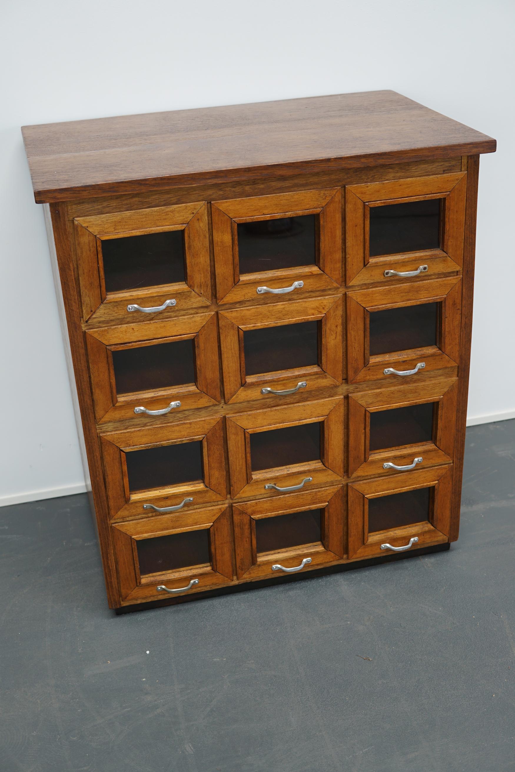 This vintage haberdashery shop cabinet originates from the United Kingdom. The piece is made from oak and features 12 drawers which measure 35 x 17 x 14 cm on the inside.