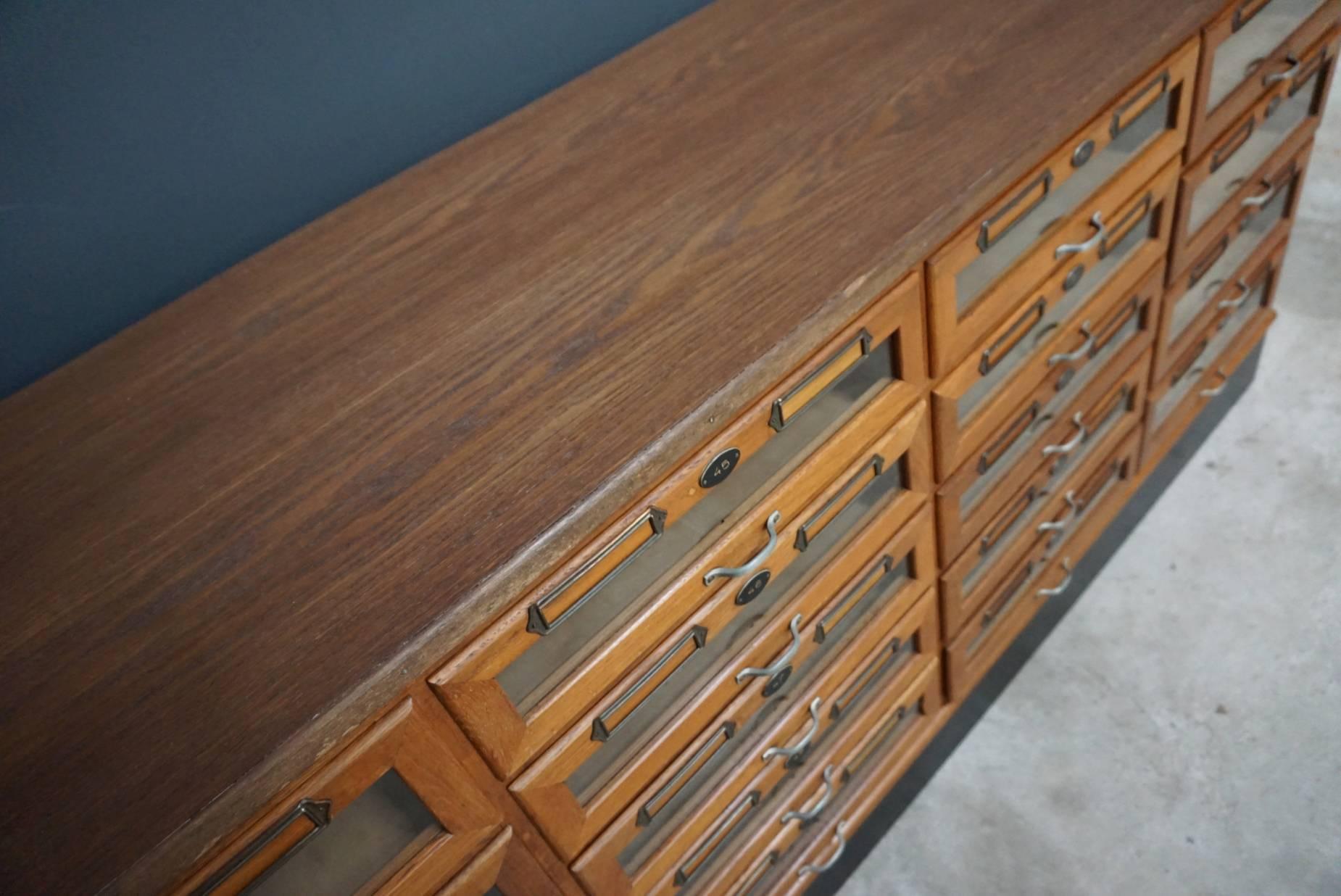 This vintage haberdashery shop cabinet originates from the United Kingdom. It is made from oak and features 18 drawers. The inside of the left and right drawers measure 45 x 36 x 12 cm and the middle two 45 x 36 x 9 cm.