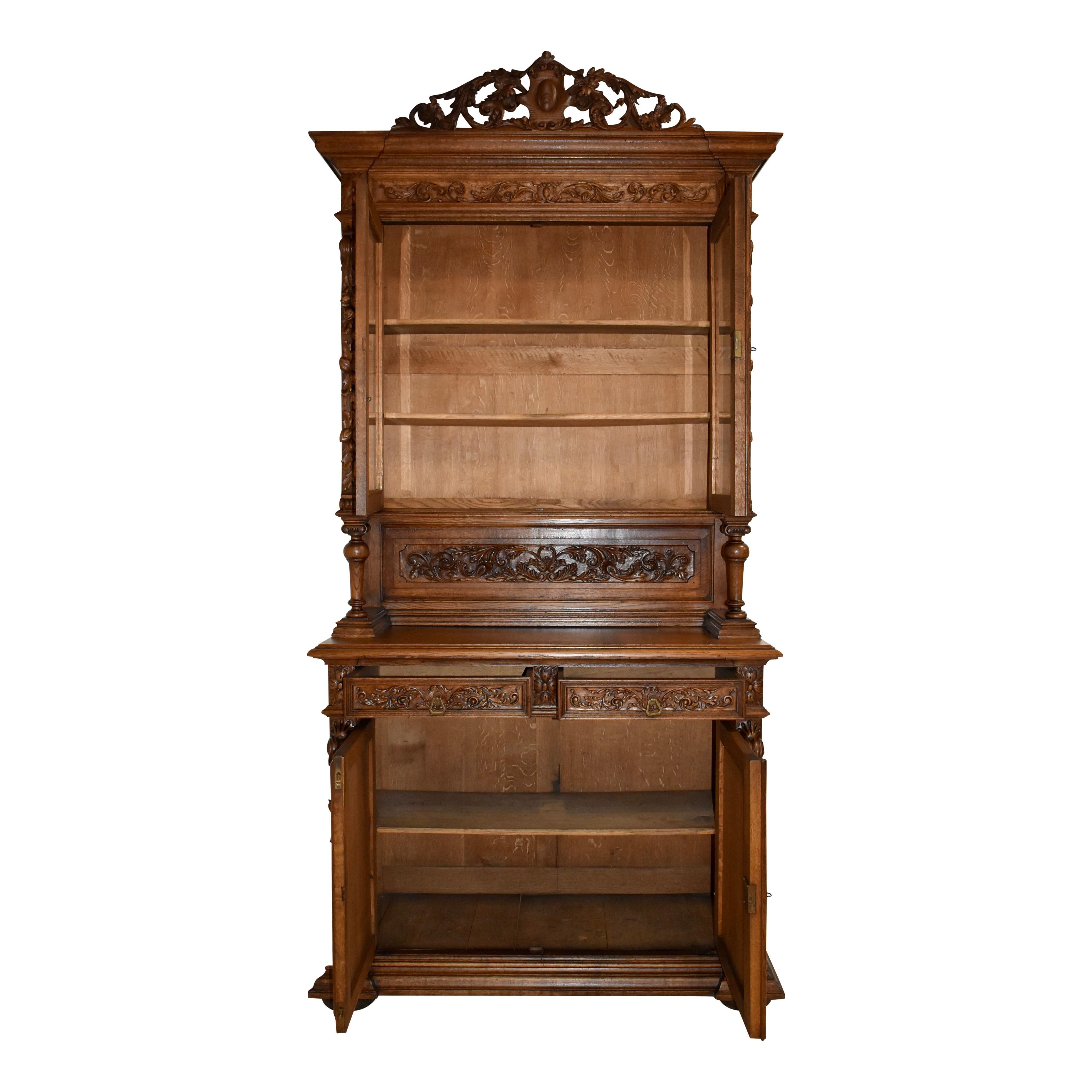 Substantial in size and beauty, this oak buffet is adorned with carvings from the hunt, scrolled foliage, flowers, and the fruit of the vine. It showcases a pierced crown of scrolled leaves with an oval medallion at the center, an upper cabinet with