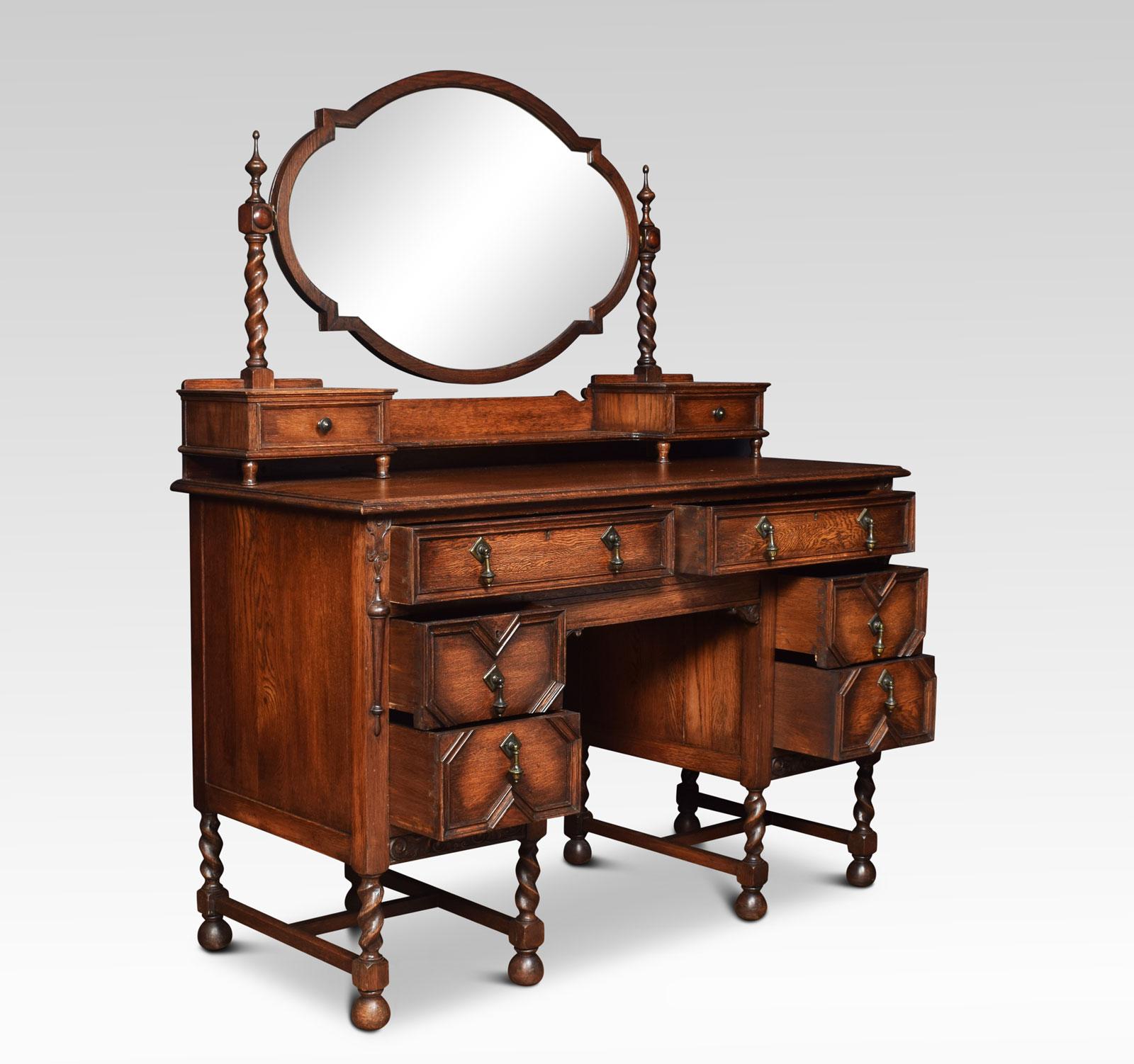 Oak Jacobean style dressing table, the raised super structure with oval mirror plate raised on barley twist columns and short draws to the base. To the large rectangular oak top above an arrangement of six draws with brass drop handles and oak-lined