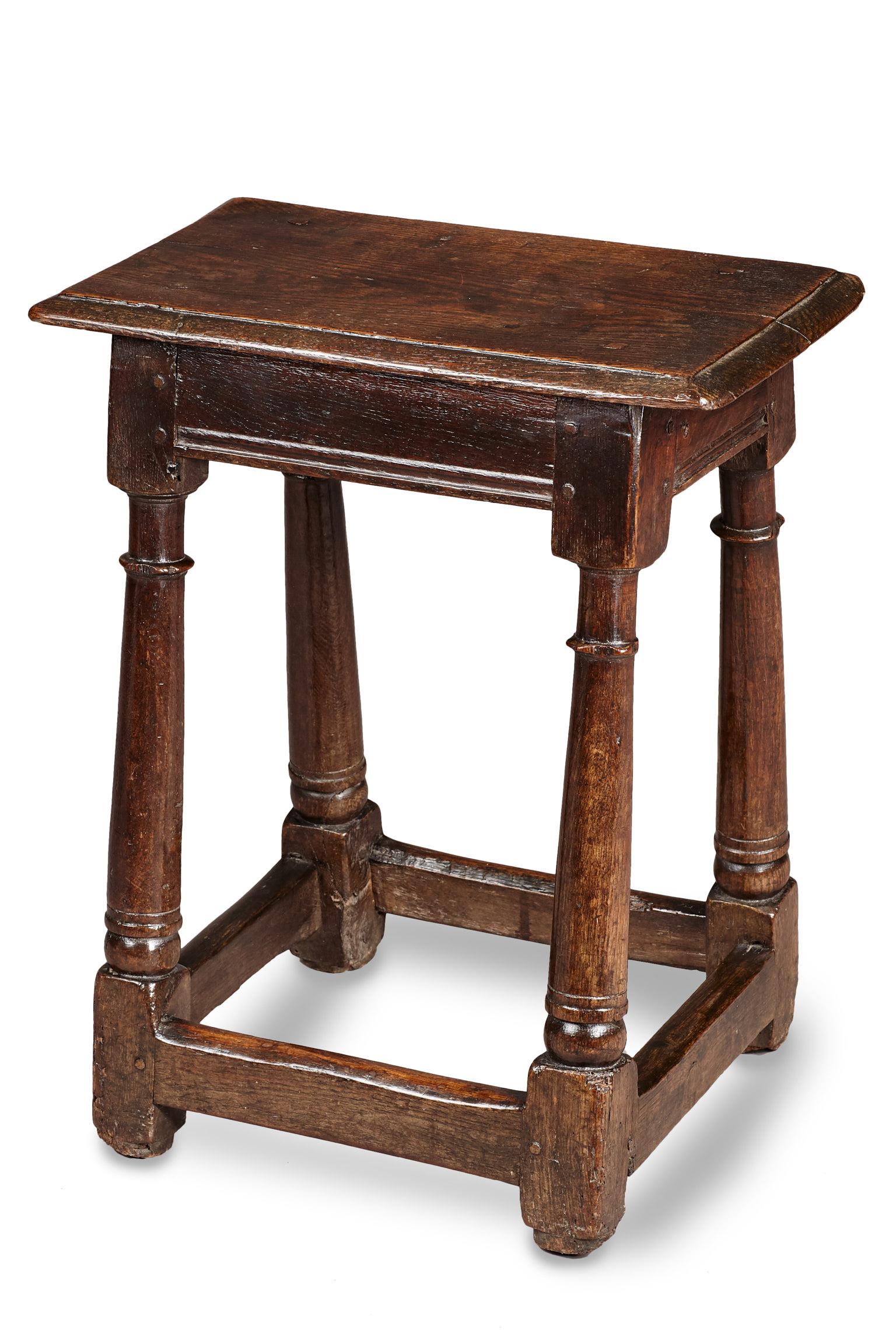 Charles II oak joined stool, English, circa 1680.

The rectangular molded top above lightly molded frieze rails joined by boldly splayed plain baluster legs terminating in a ball, with plain lower stretchers.