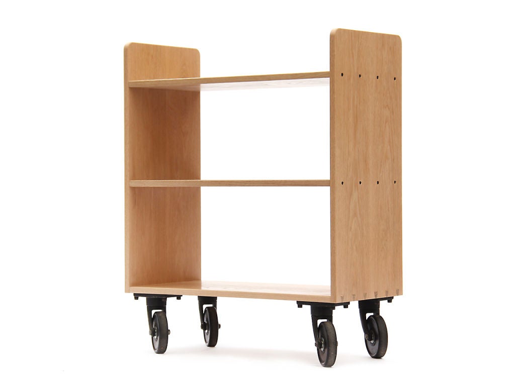 A dovetailed three shelf library cart on cast iron casters.