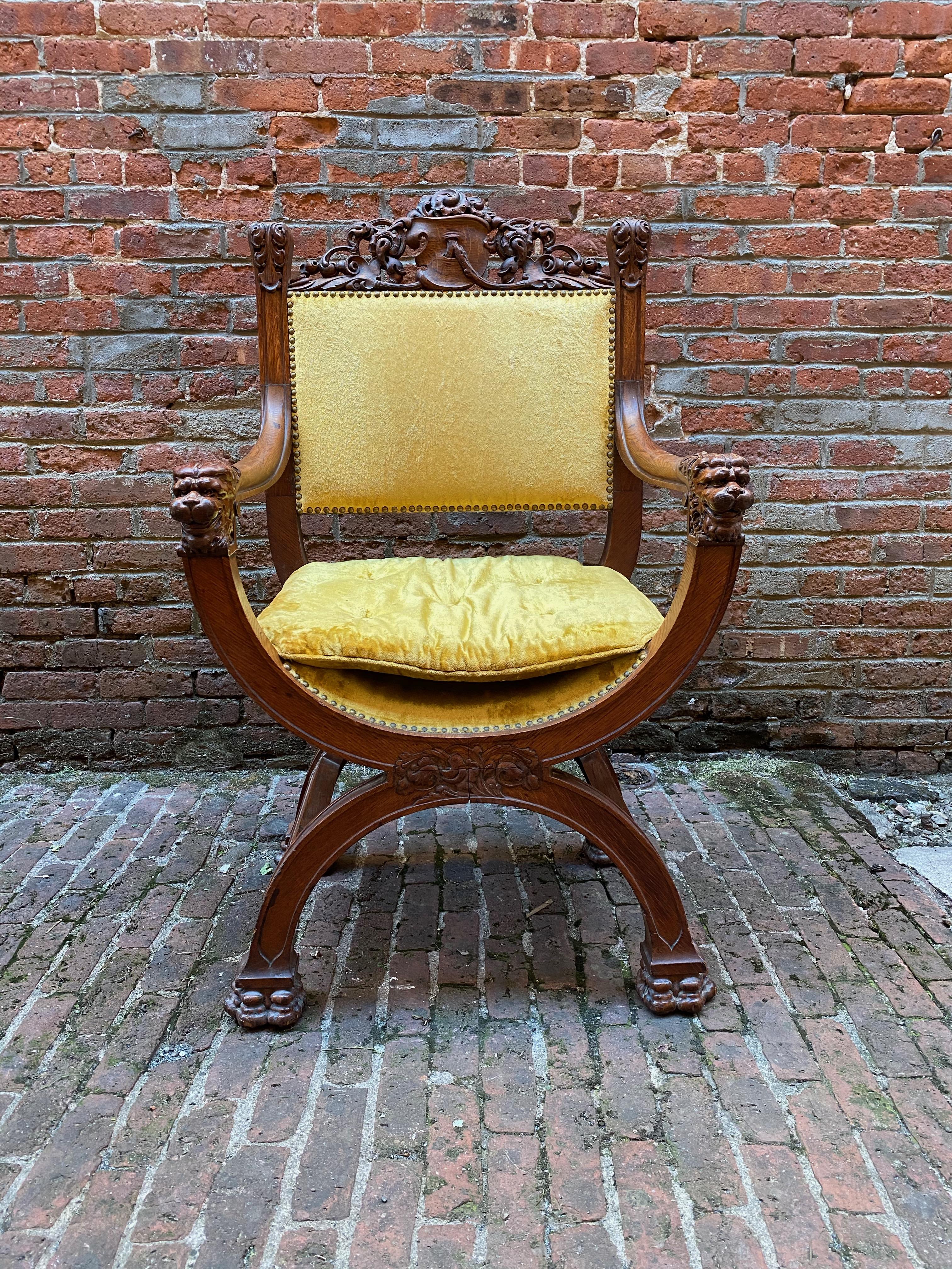 Carved oak Savonarola chair. Sumptuously carved paw feet, lions heads, leaf and scroll design flanking a heraldic shield. Fantastic detail and quality. Brass tacked mohair upholstery. Victorian era American showpiece, circa 1870-1890. Original