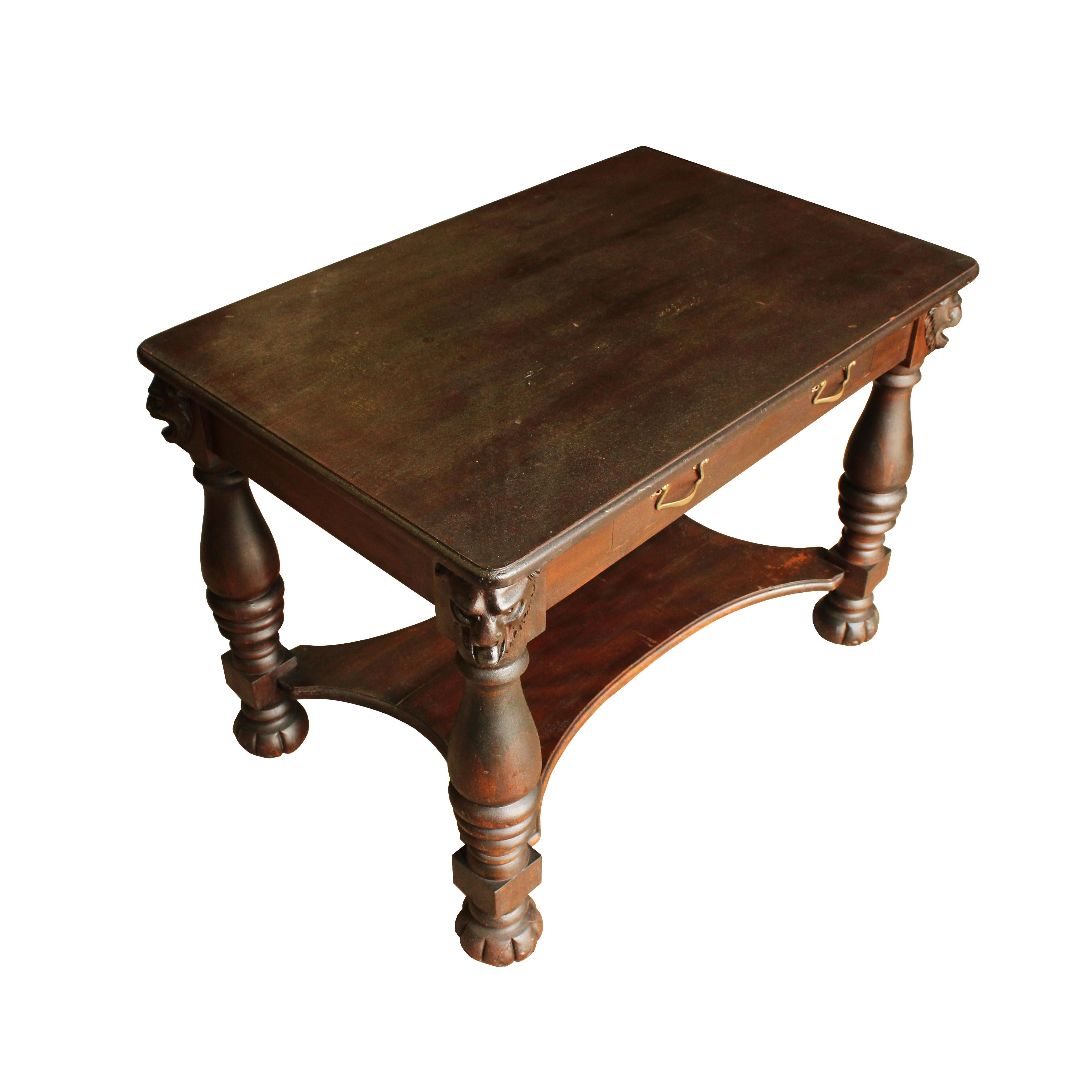 Stately enough for the library of a steel baron, this writing desk is handsome and functional. The head of a lion, mouth agape in mid-roar, adorns each leg and a single central drawer with brass bale pulls provides a place to tuck your nibs and ink.