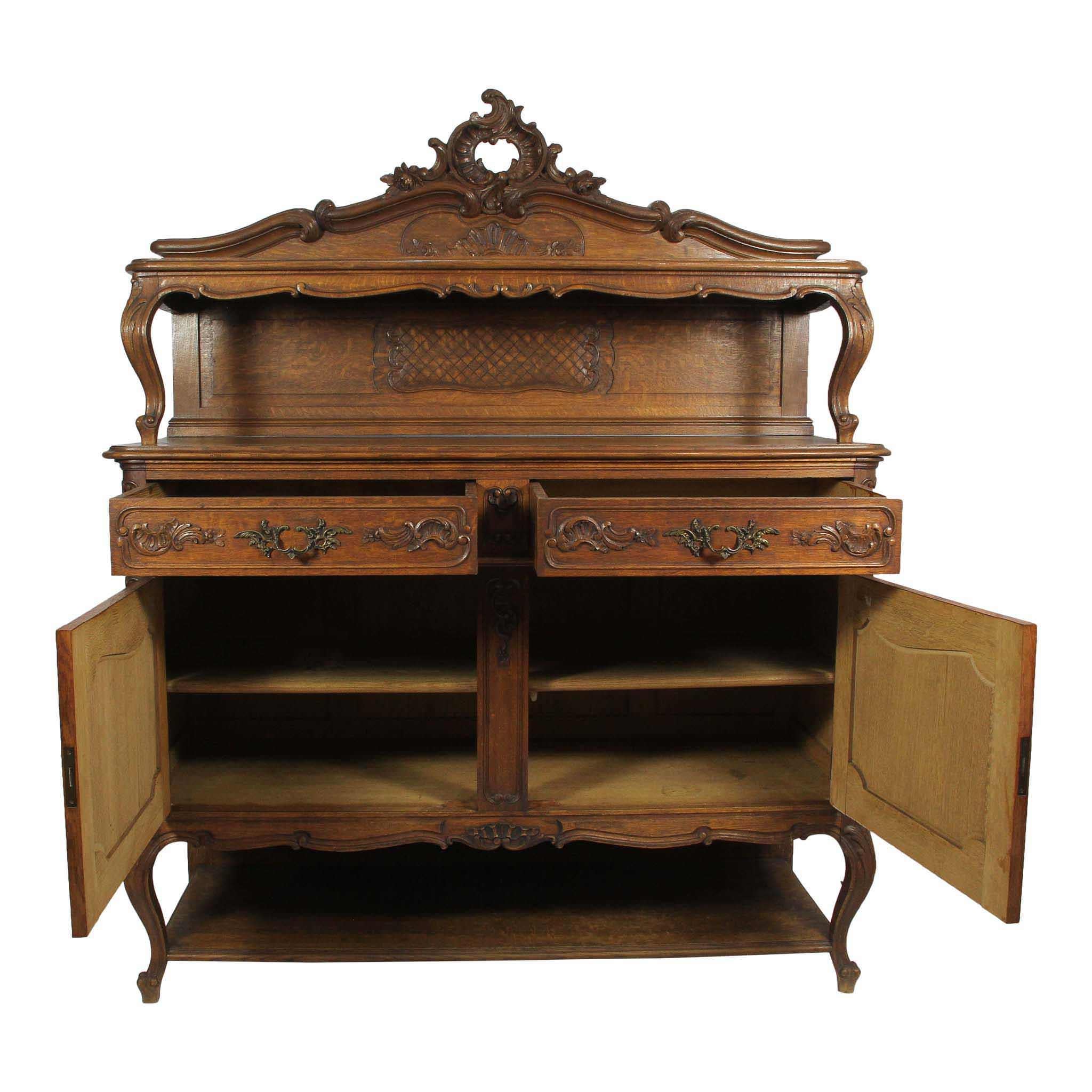 The focal point of this carved, Louis XV, oak sideboard is the backboard, which culminates in a beautiful wreath flanked by C scrolls and roses. Raised on cabriole risers and legs with acanthus leaves at the knees and whorl feet, the risers and legs