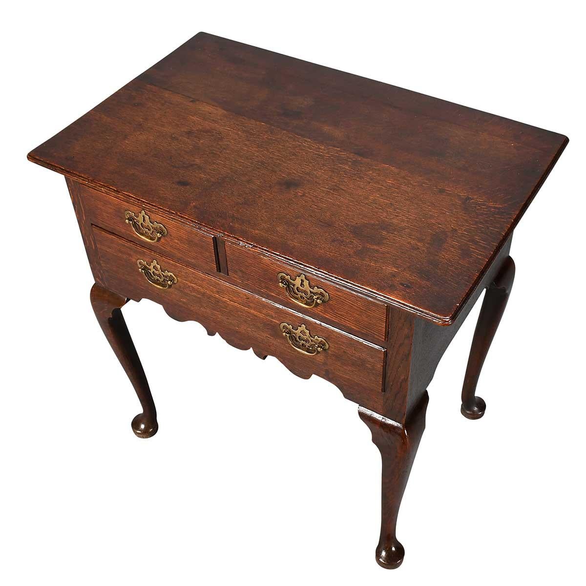 A George III period oak lowboy on four well-shaped cabriole legs ending in pad feet. Composed of two short drawers over one long drawer all over a shaped apron. Good proportions, structurally sound, and ready to use. Retaining the original hardware,