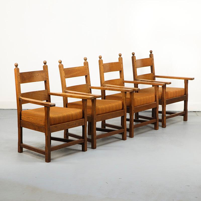 Un ensemble de quatre fauteuils en chêne au design simple mais savamment élaboré, assemblés par tenons et mortaises traditionnels pour plus de durabilité et d'authenticité. Les sièges sont recouverts d'un tissu orange vif, qui peut être facilement