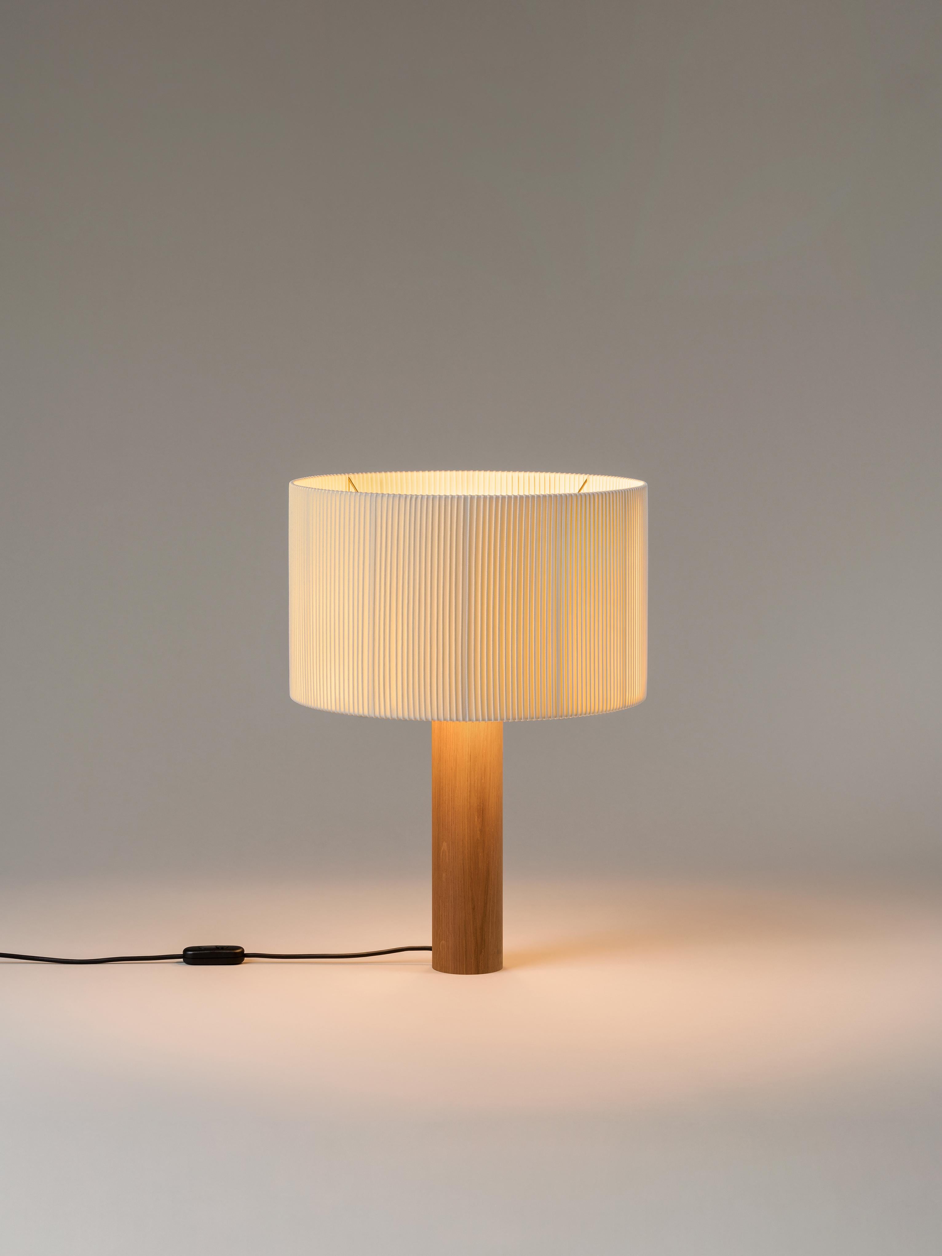 Oak Moragas table lamp by Antoni de Moragas Gallissà
Dimensions: D 45 x H 62 cm
Materials: oak wood.
Available in sapeli or oak wood.

A sturdy wooden cylinder supports a head with three bulbs, surrounded by a generous circular shade. The shade