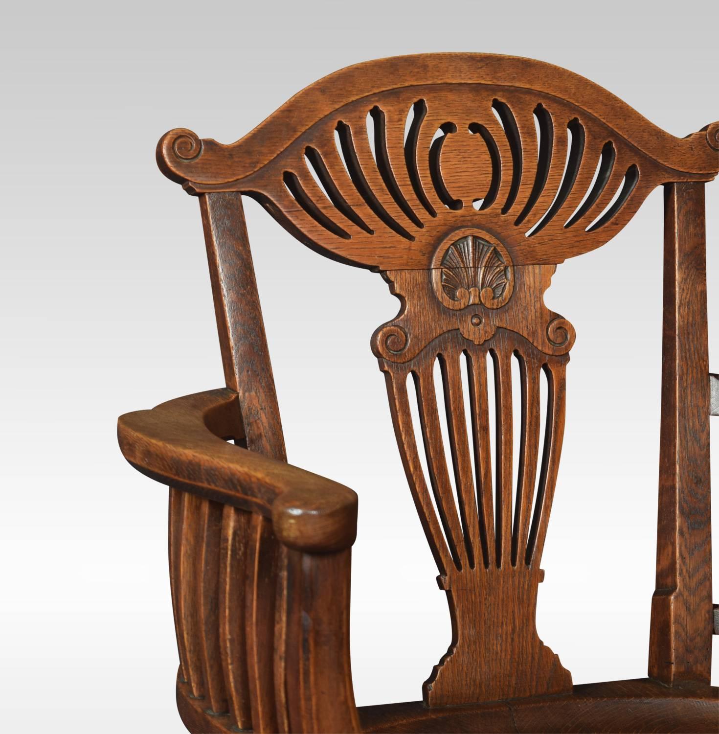 Oak office / captain’s oak revolving office chair with carved shaped pierced back and open arms above a solid oak seat. All raised up on four cabriole legs terminating in ceramic castors. The swivel mechanism inscribed H T Simmons Blackfriars London