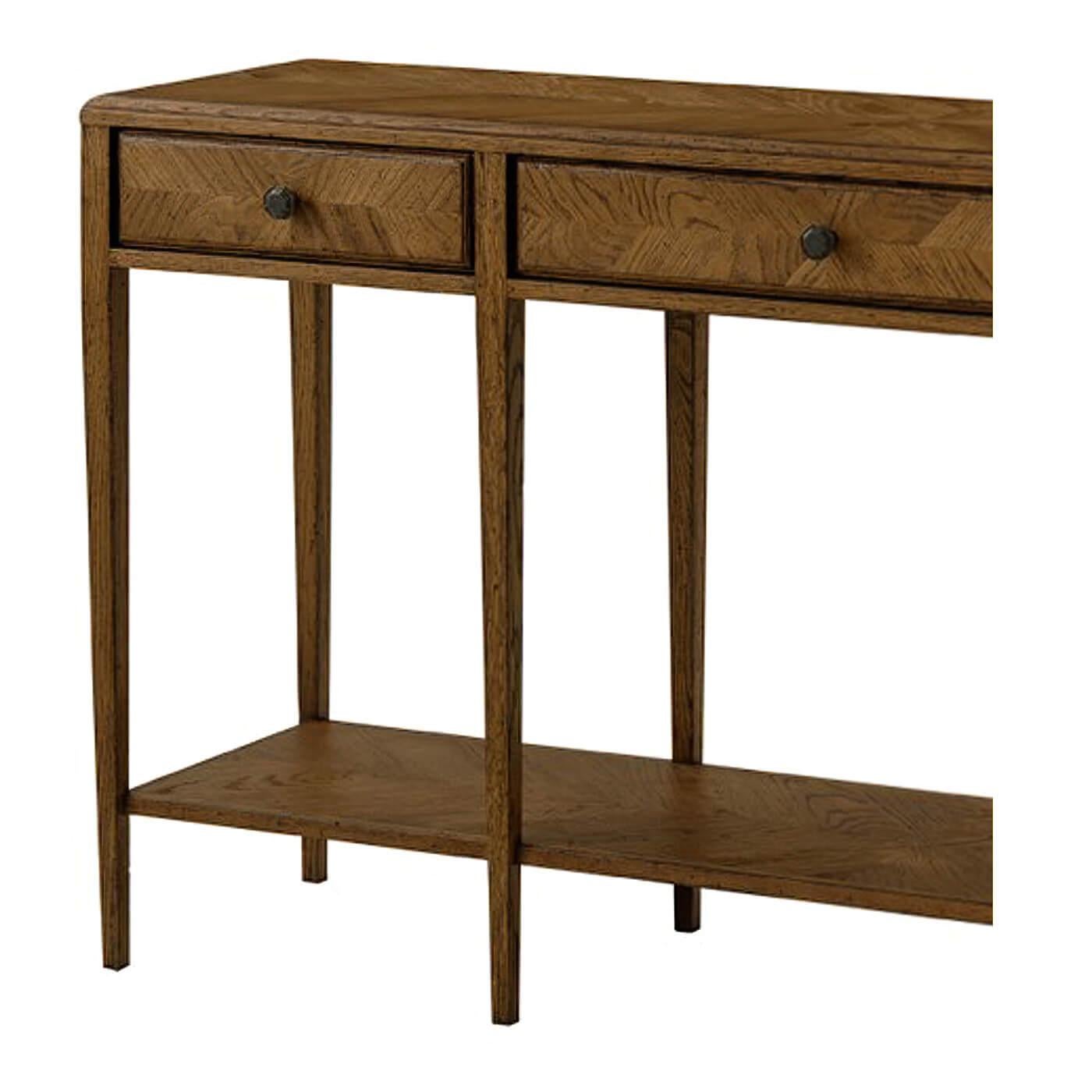 A dark oak parquetry two-tier console table with mirrored herringbone oak parquetry on its top and drawer faces. This two-tiered table includes three frieze drawers accented with Verde Bronze finished handles and has solid tapered legs. It is shown