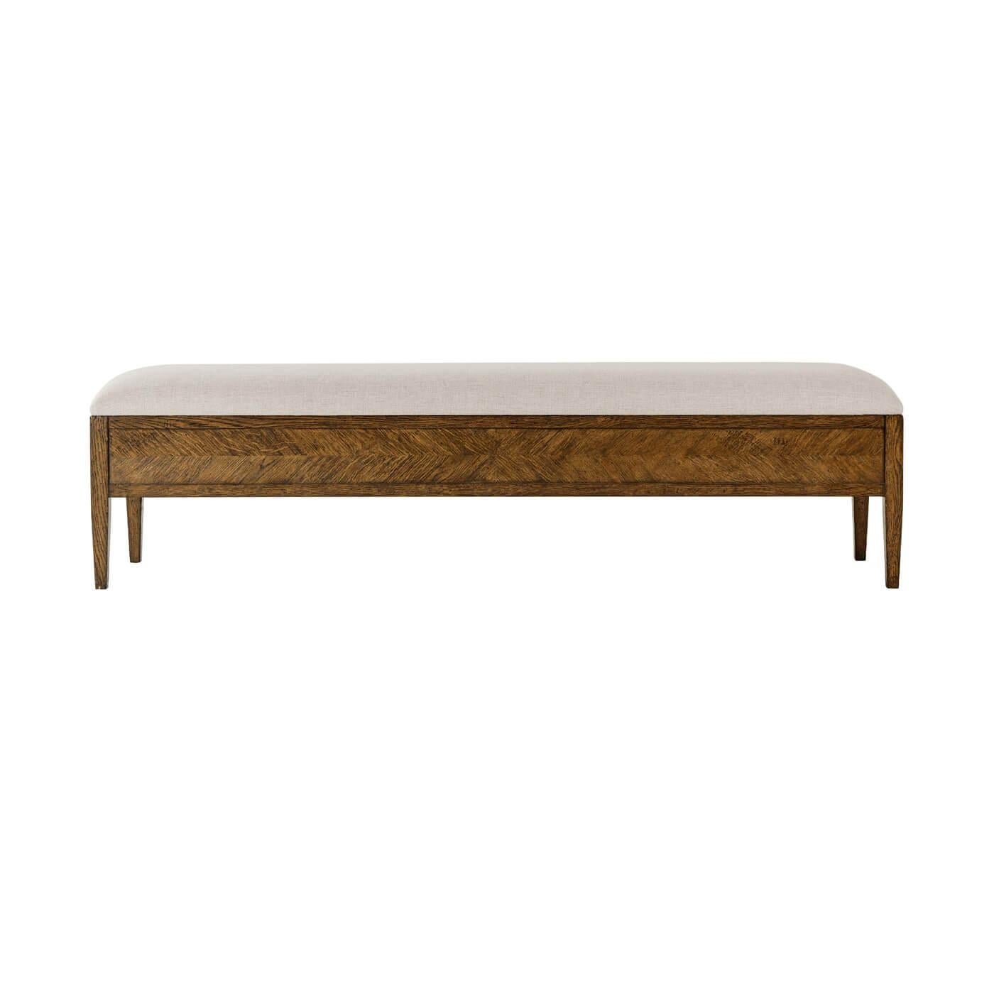 A dark oak parquetry upholstered bench with tapered legs. Crafted with rustic oak with an upholstered seat, this bench is the perfect addition to the foot of any bed or entryway. 
Shown in Dusk Finish
Shown in Linen-UP5409 fabric
Dimensions
62