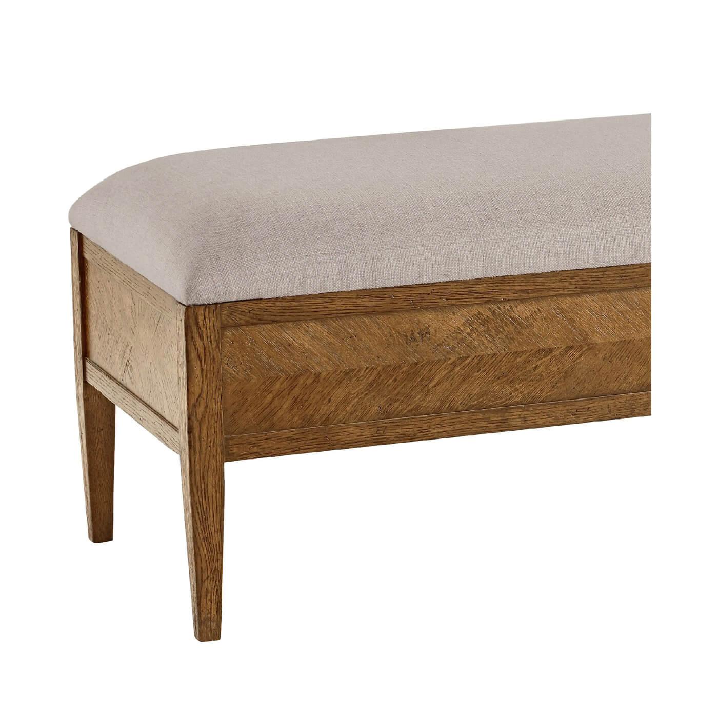 A Light oak parquetry upholstered bench with tapered legs. Crafted with rustic oak with an upholstered seat, this bench is the perfect addition to the foot of any bed or entryway. 
Shown in Dawn Finish
Shown in Linen-UP5409 fabric
Dimensions
62