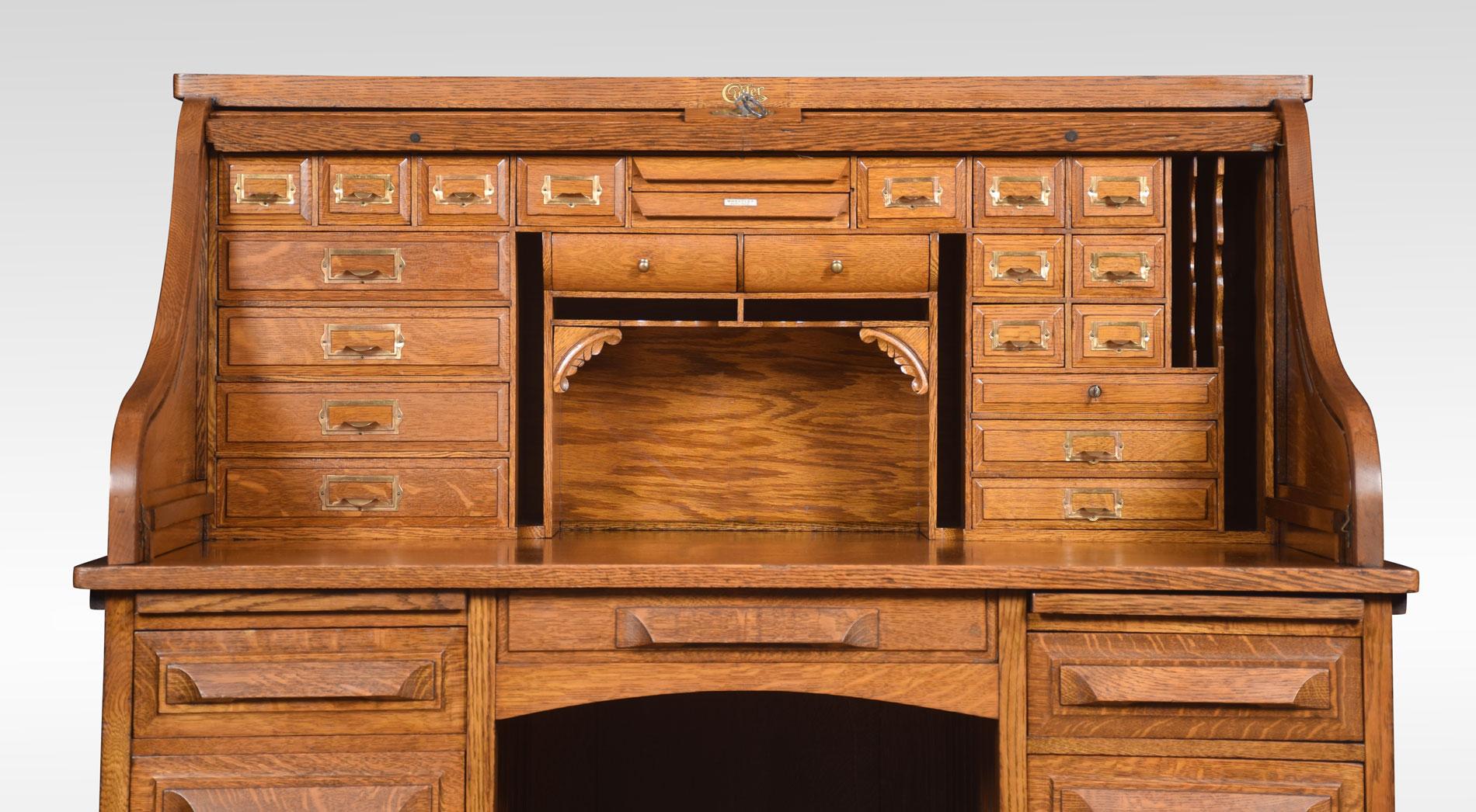 Oak double pedestal roll-top desk, the high back with the fitted interior of pigeon holes and drawers, the centre drawer flanked by pedestals having brush in slide above three short drawers and one double drawer. All raised up on plinth base.