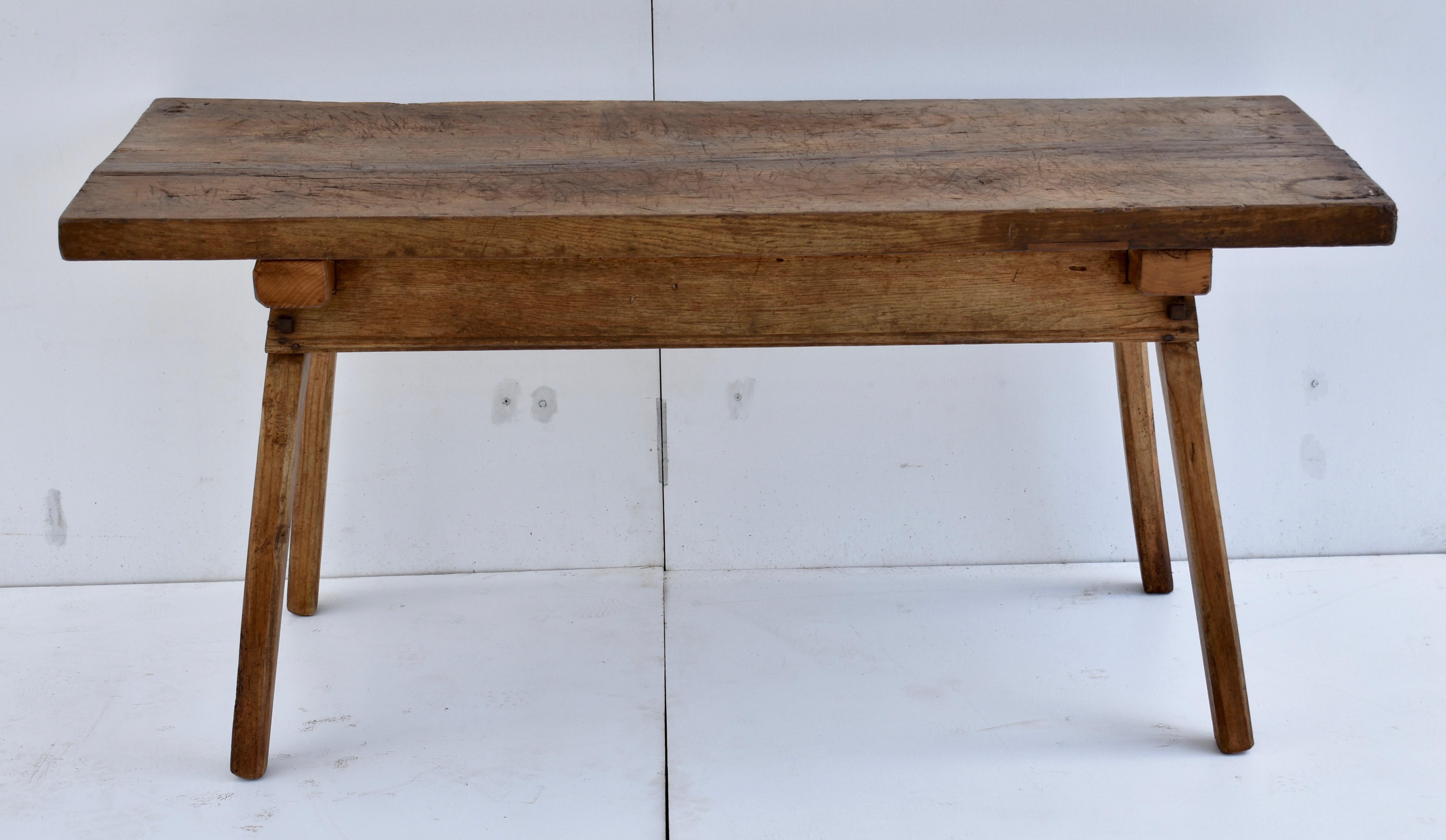 The top of this magnificent pig bench is a single massive slab of oak over two feet wide and two inches thick, beautifully chopped and scratched through decades of relatively light but purposeful use. The heavy oak legs, about 2.5” square at the