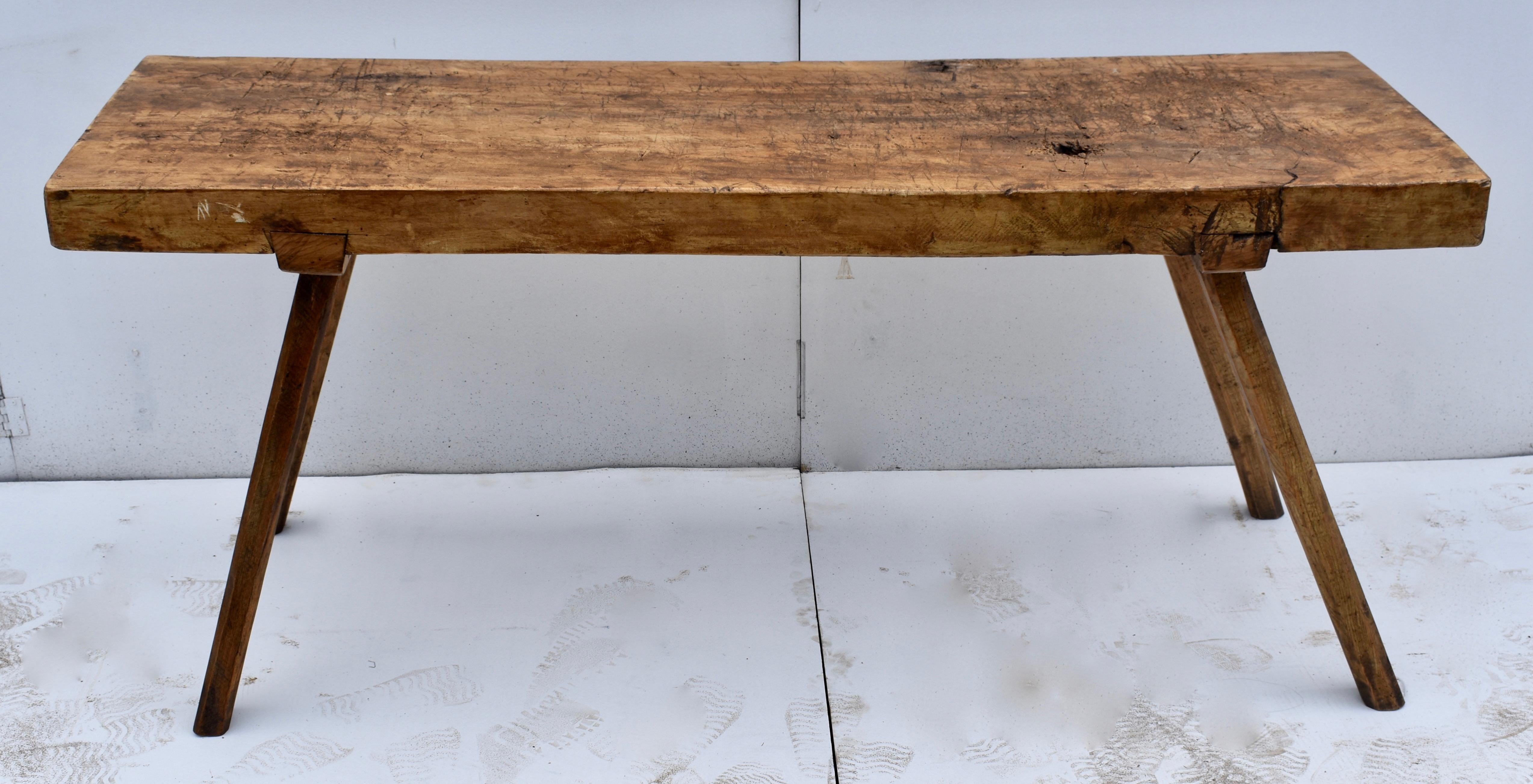 The top of this pig bench is a single slab of oak almost 3.5” thick. It is chopped and gnarled and gouged here and there, all testament to decades of purposeful use. The four slender, rough-hewn, hexagonal legs are mortised into an oak cleat, which