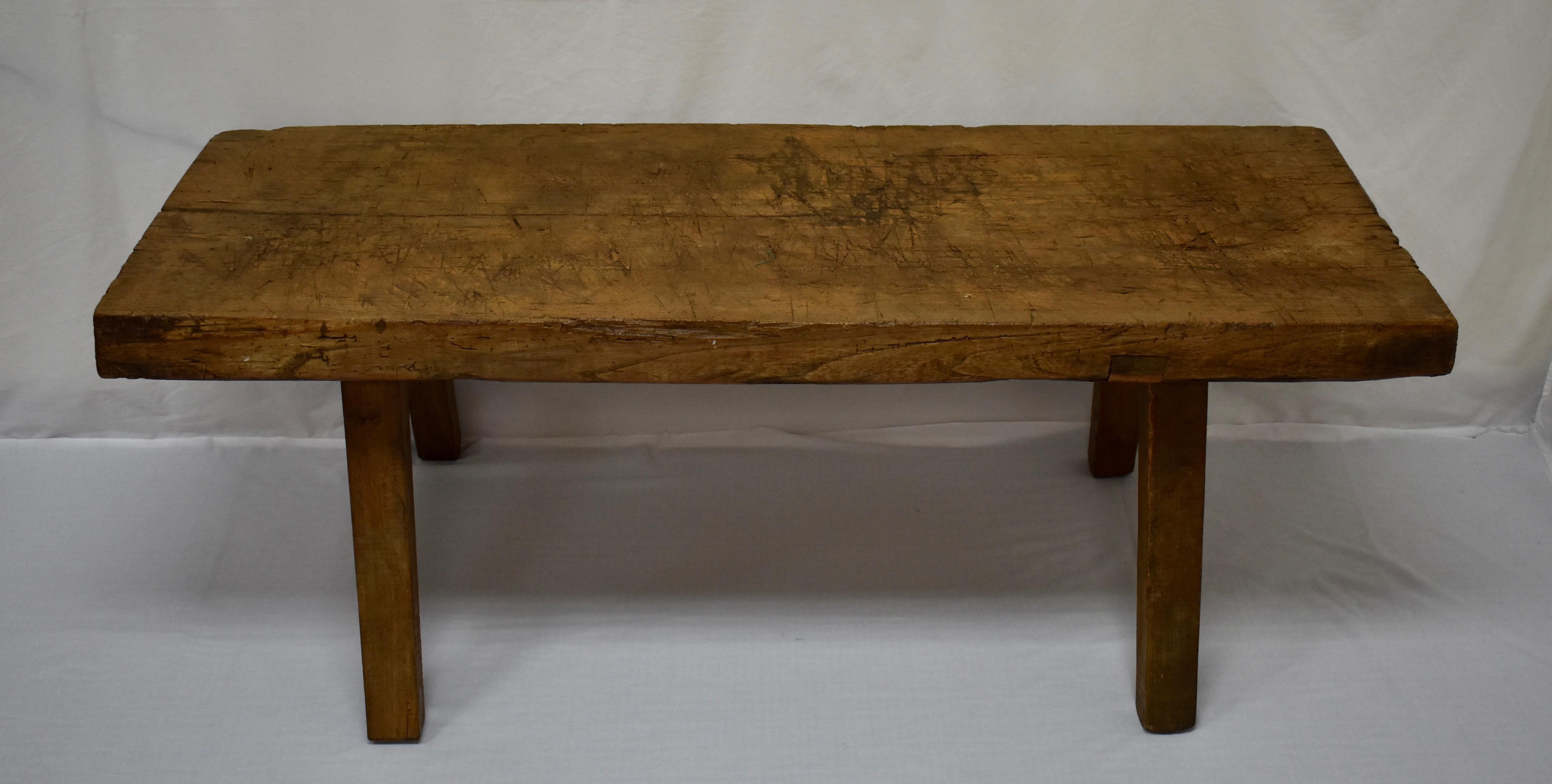 This outstanding oak pig bench low table sits on four 2”x2.5” sturdy splayed legs which are mortised into the underside of the top. The top itself is a single slab of oak 3” thick, which has developed a beautiful patina over the decades. It is